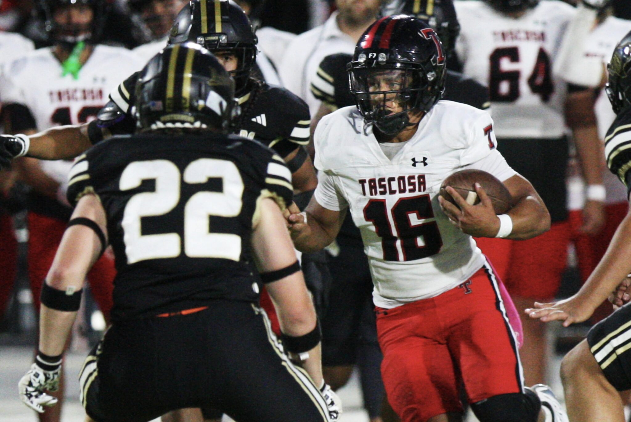 IMG_8134 | Press Pass Sports Football player in a white jersey with red pants holds the ball, surrounded by defenders in black and gold.