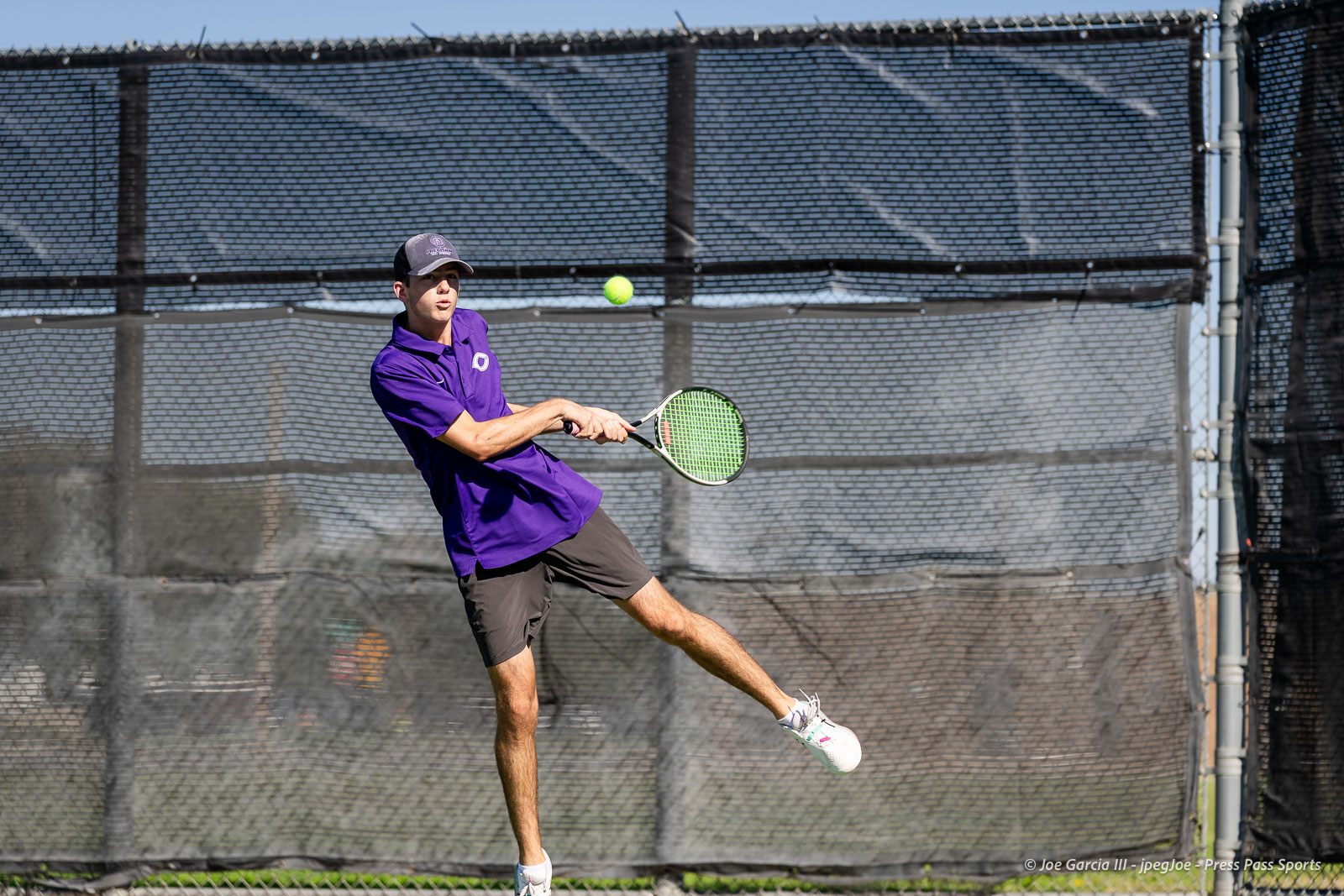 canyon-regional-tennis-72 | Press Pass Sports Male tennis player in a purple shirt and gray shorts hitting a forehand on an outdoor court, ball just in front of him.