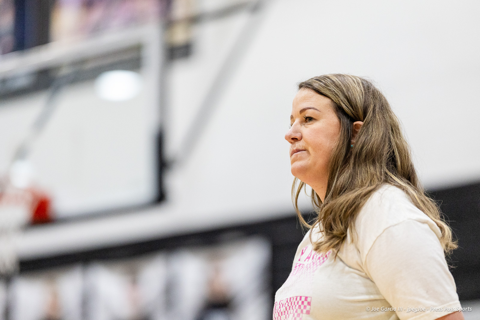 canyon-vs-west-plains-2026-27 | Press Pass Sports Woman in profile facing right, wearing a light shirt, indoors at a large event or gym.