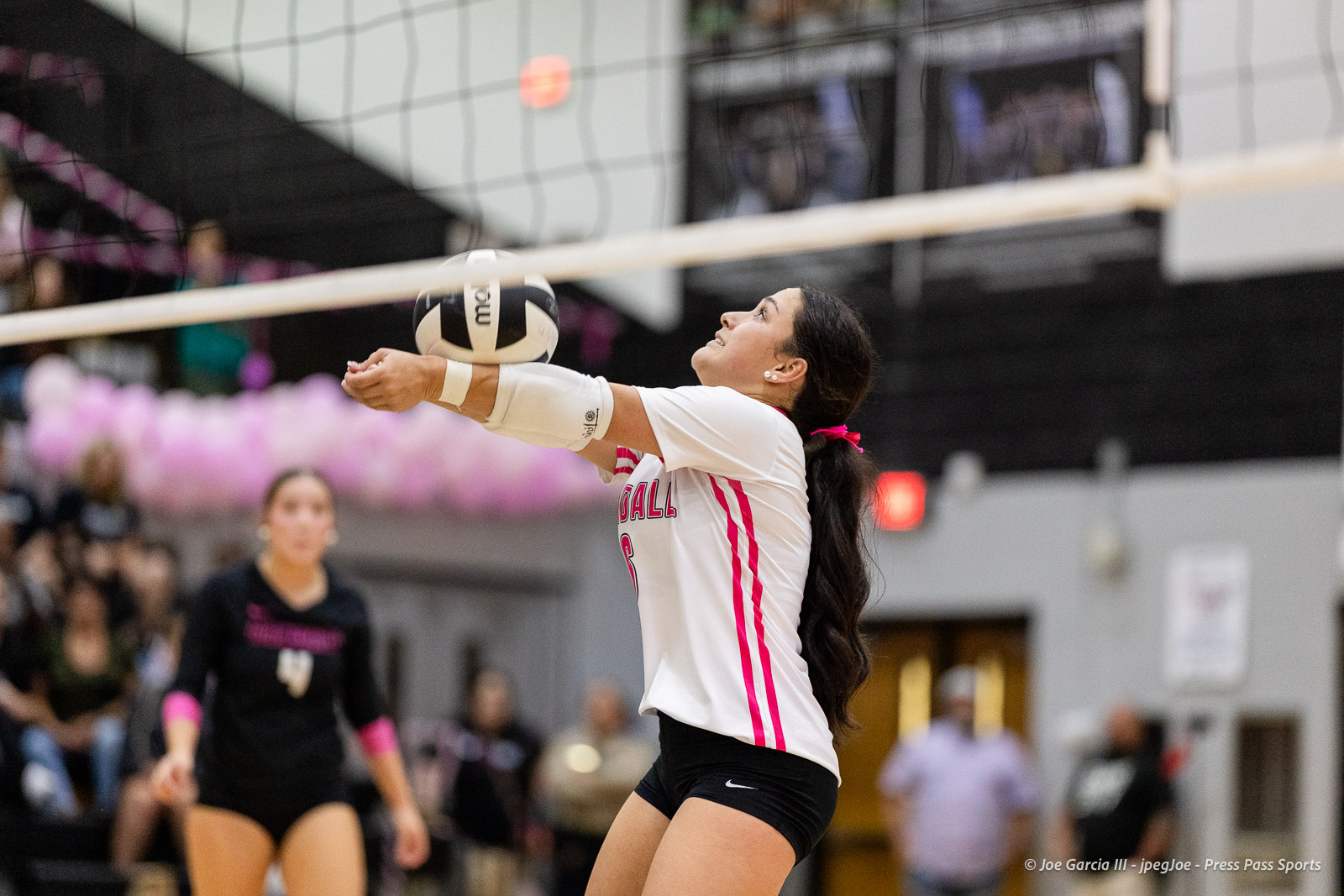 canyon-vs-west-plains-2026-34 | Press Pass Sports Female volleyball player in white and pink jumps to save the ball at the net during a match.