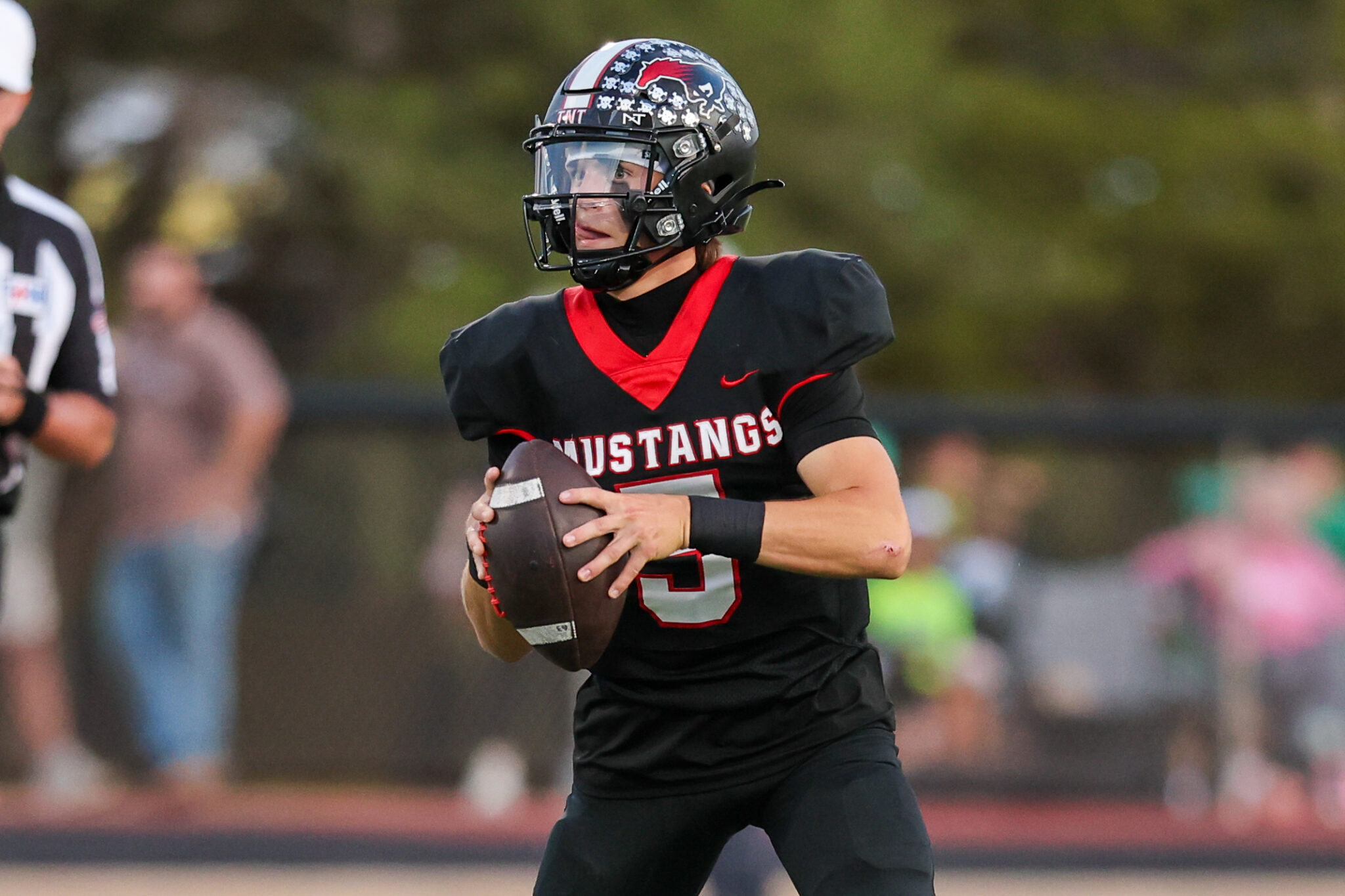 Seabolt Chase-17322 | Press Pass Sports Football player in a black and red Mustangs uniform runs with the ball during a game.