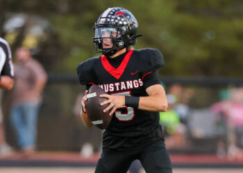 Seabolt Chase-17322 | Press Pass Sports Football player in a black and red Mustangs uniform runs with the ball during a game.