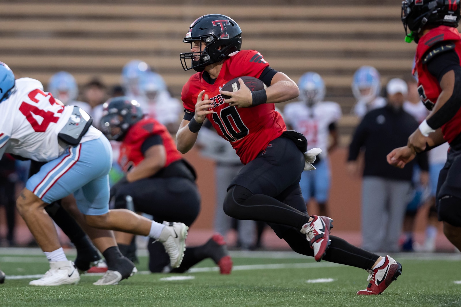 MHS-THS-FB-3 | Press Pass Sports Quarterback in red jersey (number 10) running with the football, looking downfield as defenders approach.