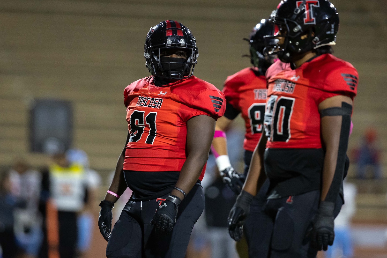 MHS-THS-FB-15 | Press Pass Sports Football players in red jerseys and black helmets stand together on a field, foreground player wearing number 91.