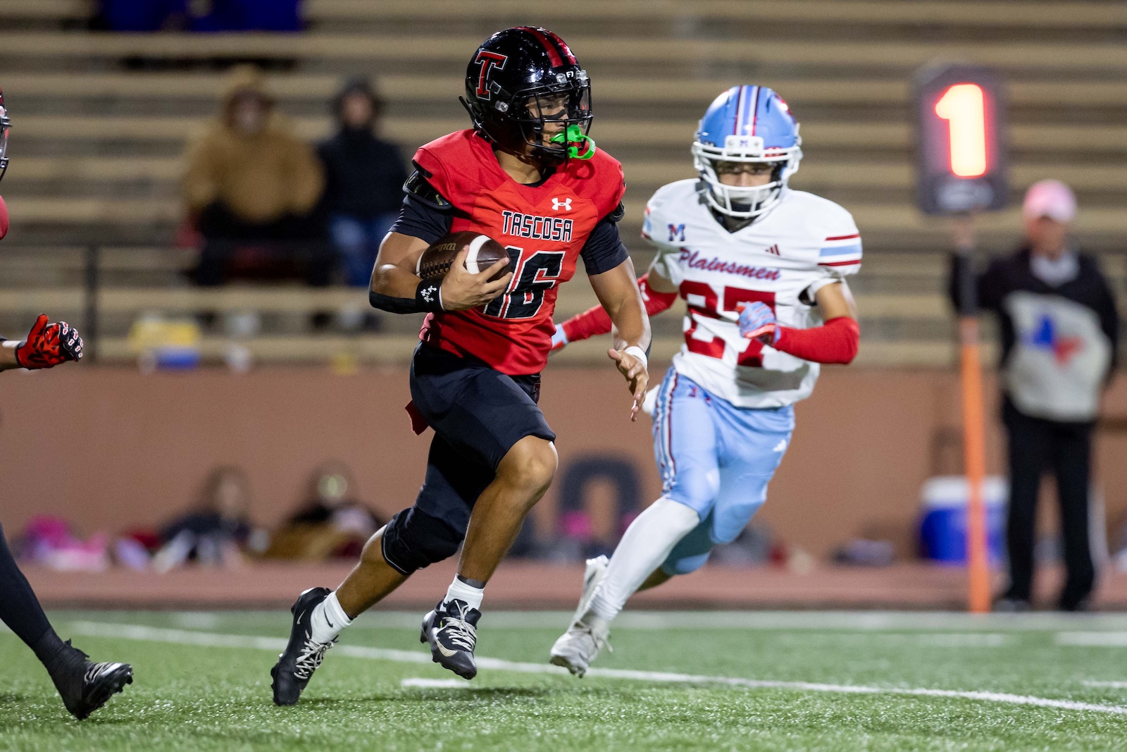 MHS-THS-FB-33 | Press Pass Sports Player in red Tascosa jersey runs with the football, advancing down a turf field while defenders pursue.