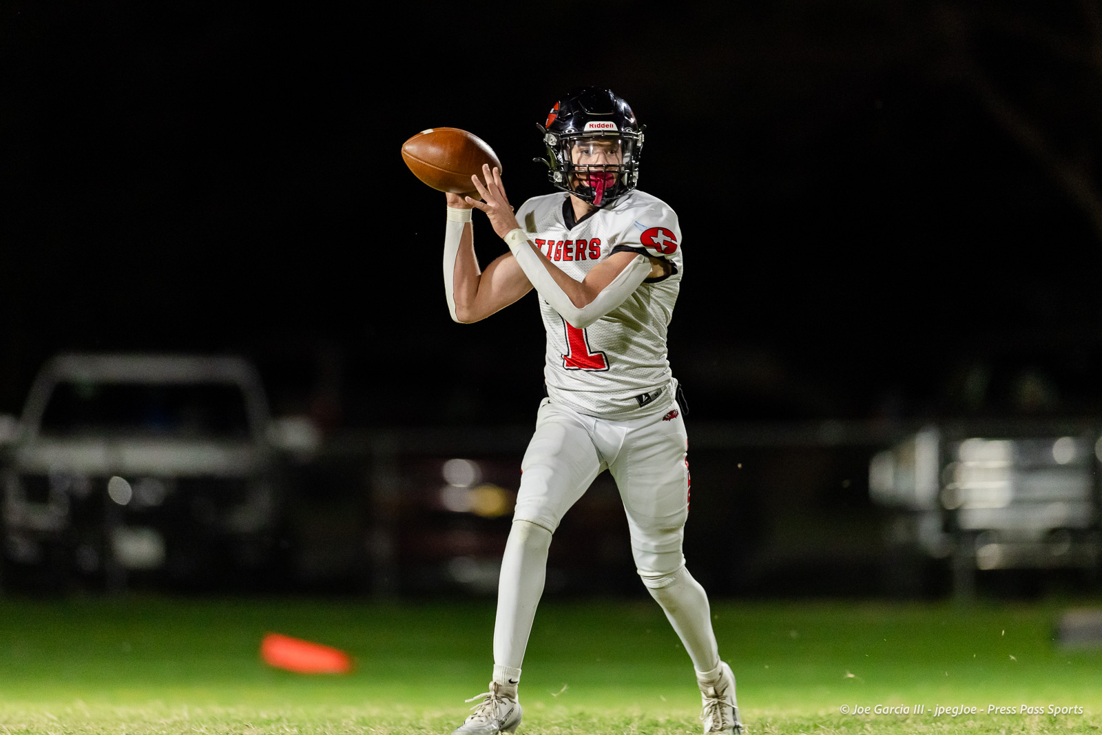 groom-vs-follett-football-jpegJoe-pps-14 | Press Pass Sports Quarterback in a white Tigers jersey throws a football during a night game under stadium lights.