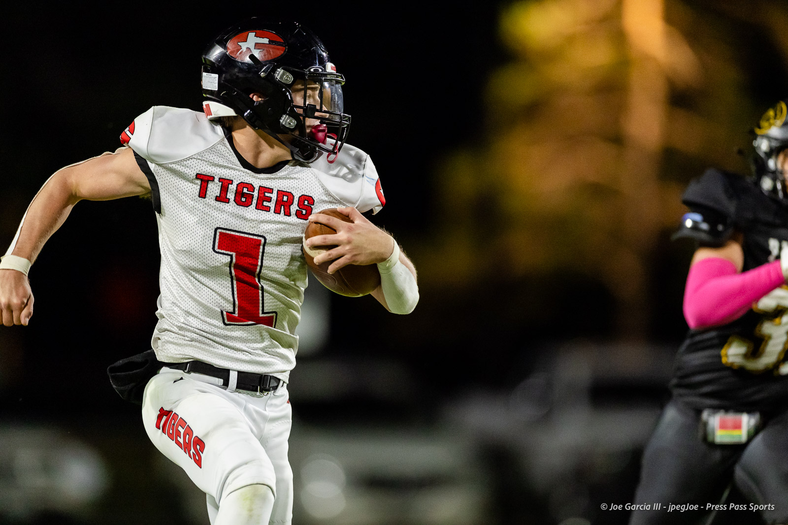 groom-vs-follett-football-jpegJoe-pps-23 | Press Pass Sports Football player in white'Tigers' jersey runs with ball during night game, aimed forward with helmet and red number 1 visible on chest.