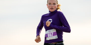 Female runner in a purple long-sleeve top with bib 867, mid-race outdoors.