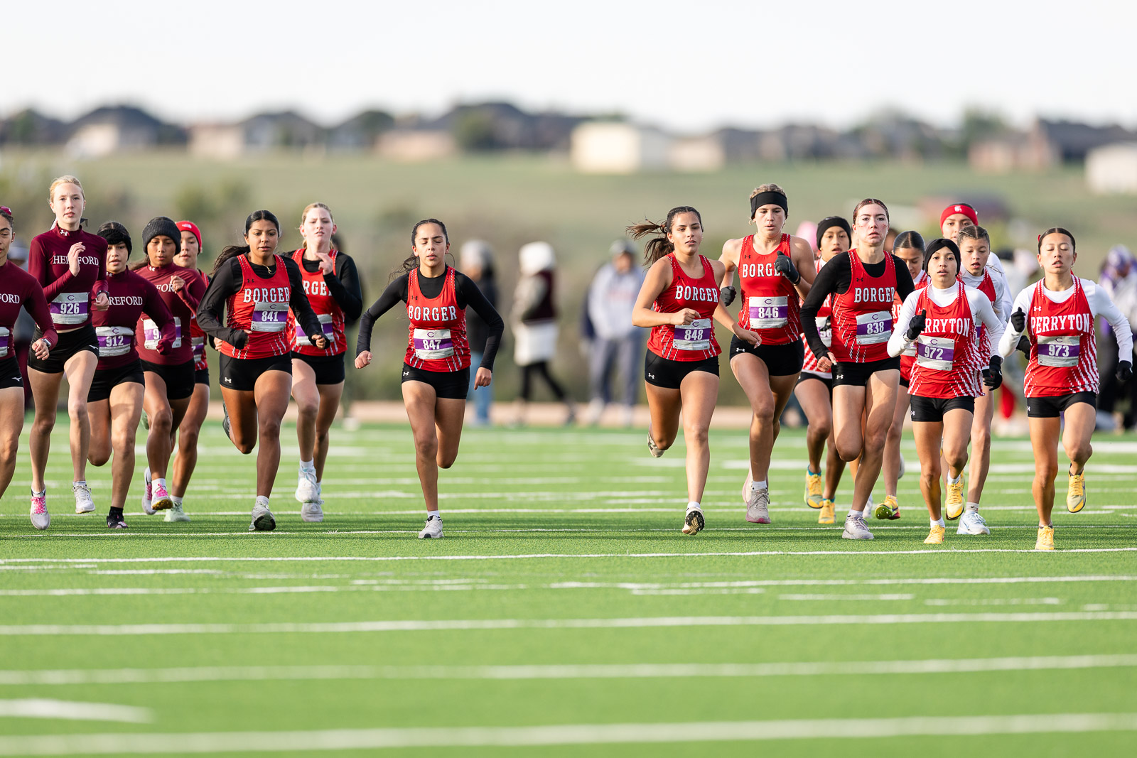 3A-4A-district-xc-jpegJoe-pps-1 | Press Pass Sports Group of female cross-country runners in red and black uniforms sprint at the start on a green track field.