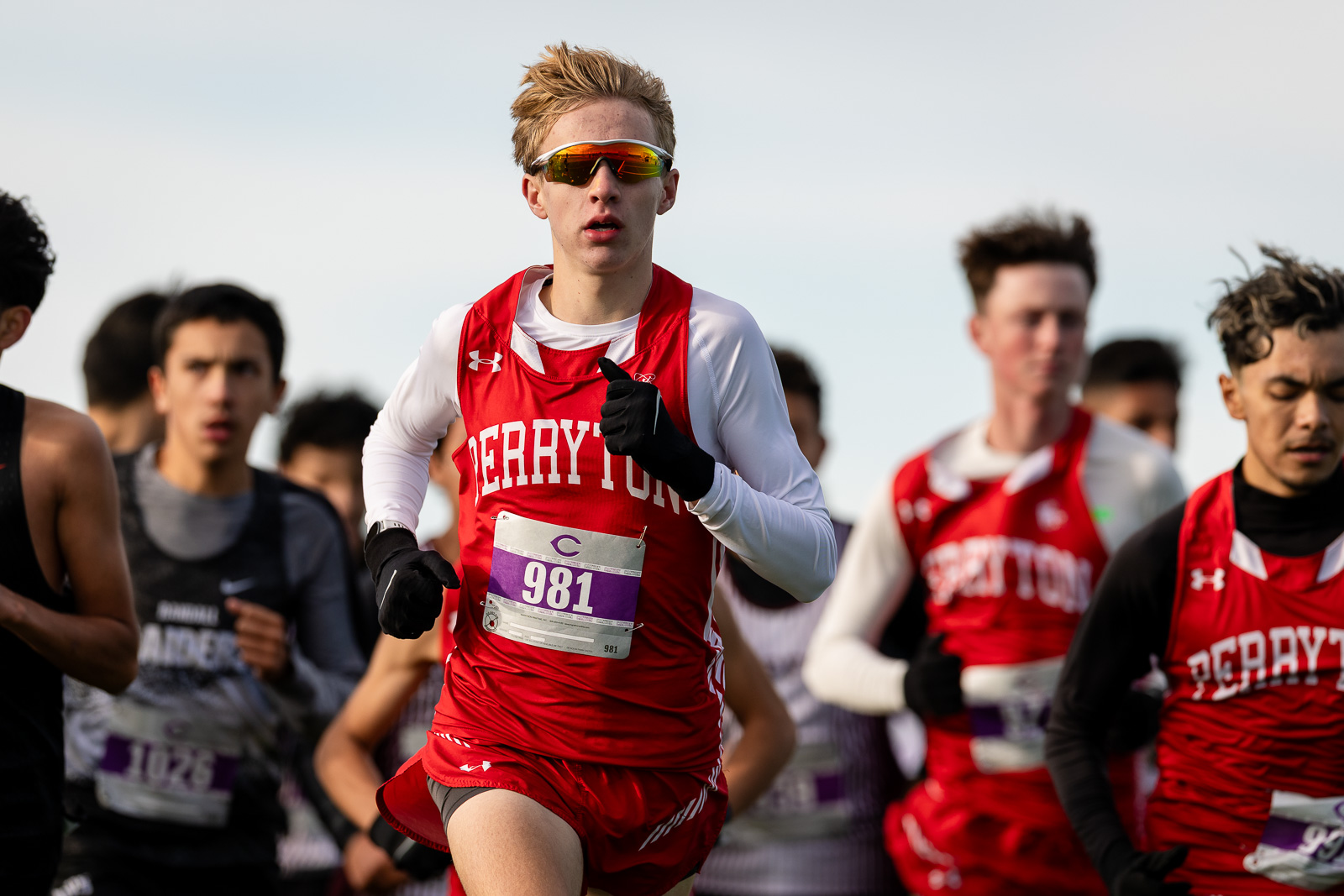 district-3a-4a-cross-country-jpegJoe-pps-73 | Press Pass Sports Young male runner in red and white uniform with bib 981 leading a cross-country race.