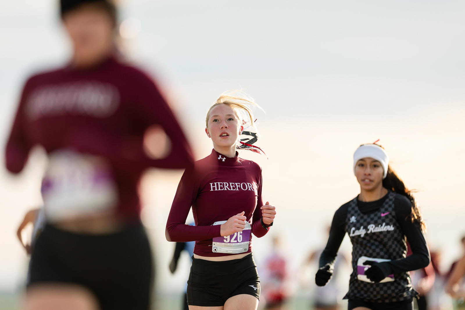 3A-4A-district-xc-jpegJoe-pps-9 | Press Pass Sports Female runner in a maroon'HEREFOR' top, bib 926, running in a sunny race.
