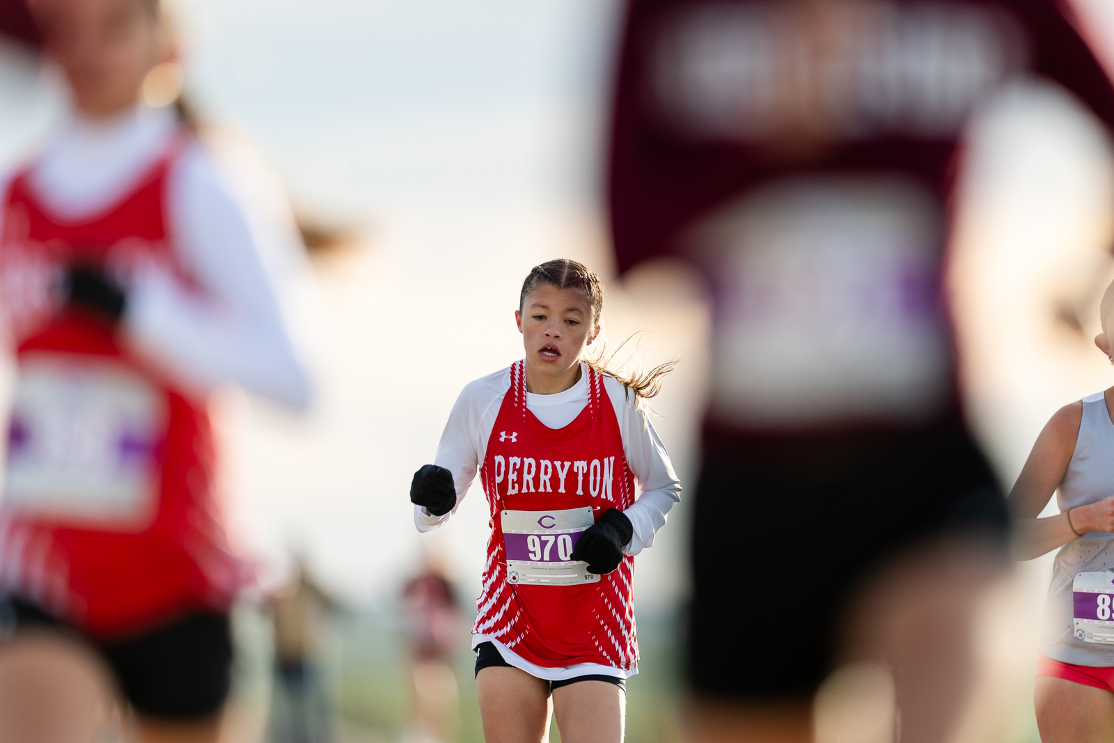 3A-4A-district-xc-jpegJoe-pps-12 | Press Pass Sports Young female runner in a red Perryton jersey with bib 970, mid-race on a sunny day соntrolled stride.