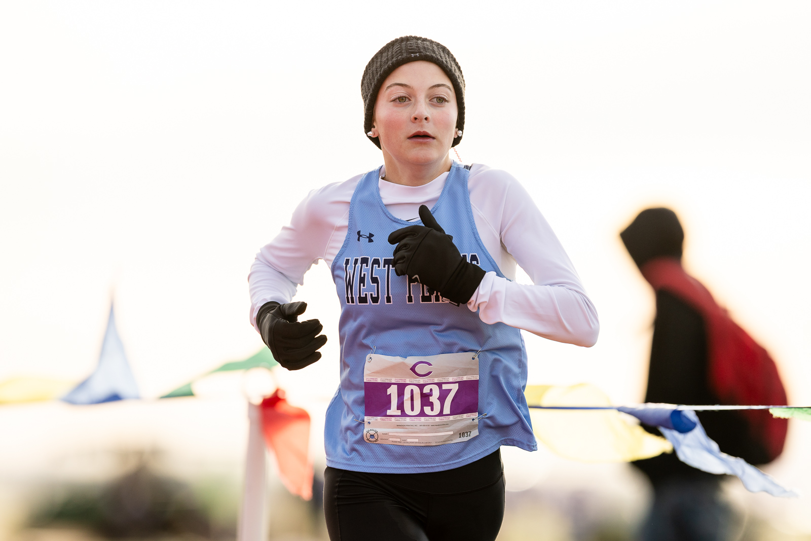 3A-4A-district-xc-jpegJoe-pps-16 | Press Pass Sports Female runner in a blue race singlet with bib 1037, wearing a beanie and black gloves, mid-race outdoors