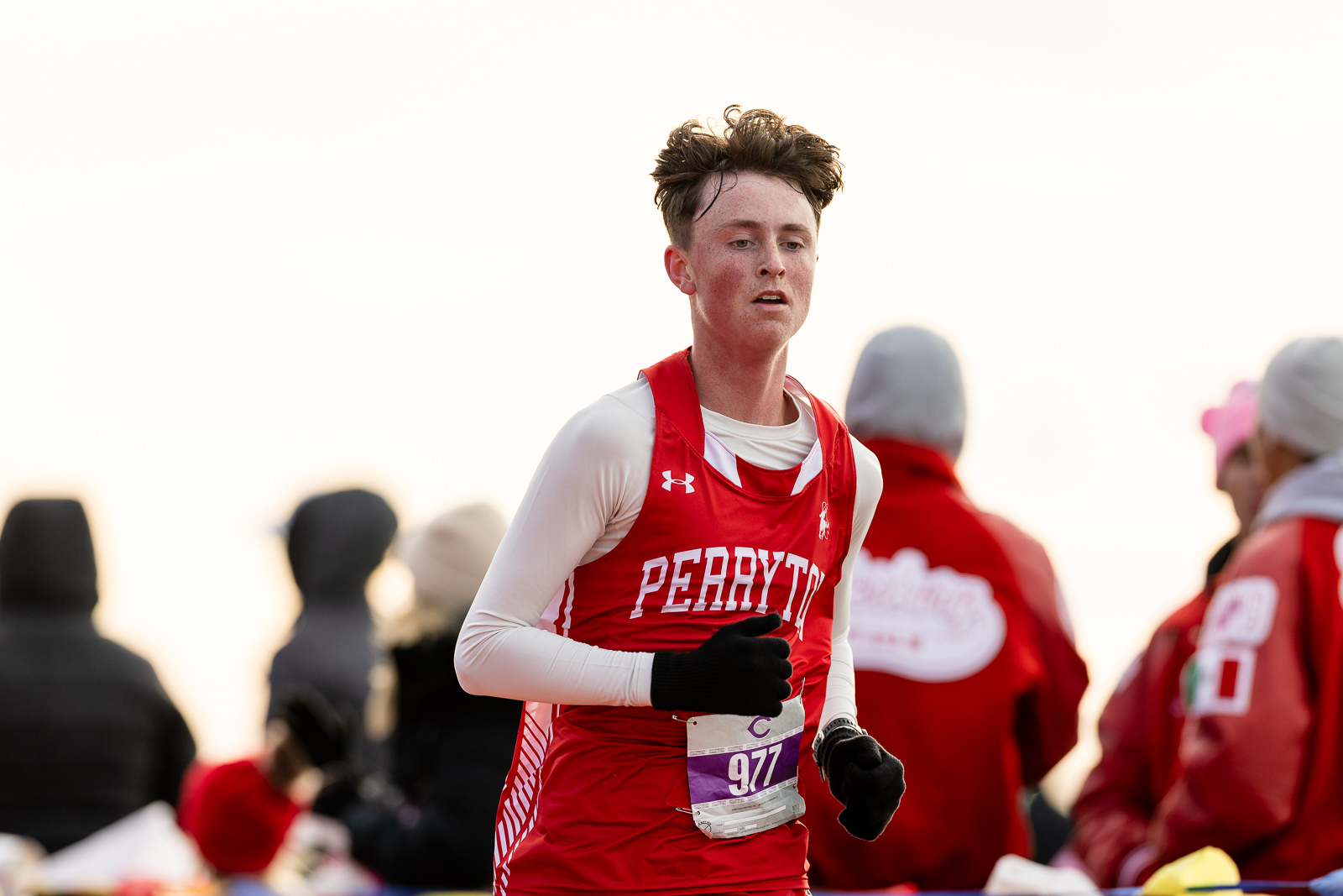 3A-4A-district-xc-jpegJoe-pps-46 | Press Pass Sports Male runner in a red Under Armour singlet with white sleeves, bib 977, mid-stride during a race.