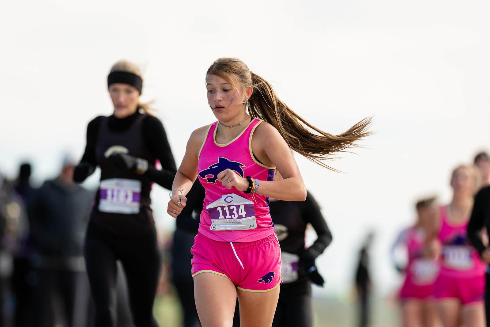 3A-4A-district-xc-jpegJoe-pps-68 | Press Pass Sports Young girl in a pink running outfit sprinting during a race; bib 1134, hair flying behind her.
