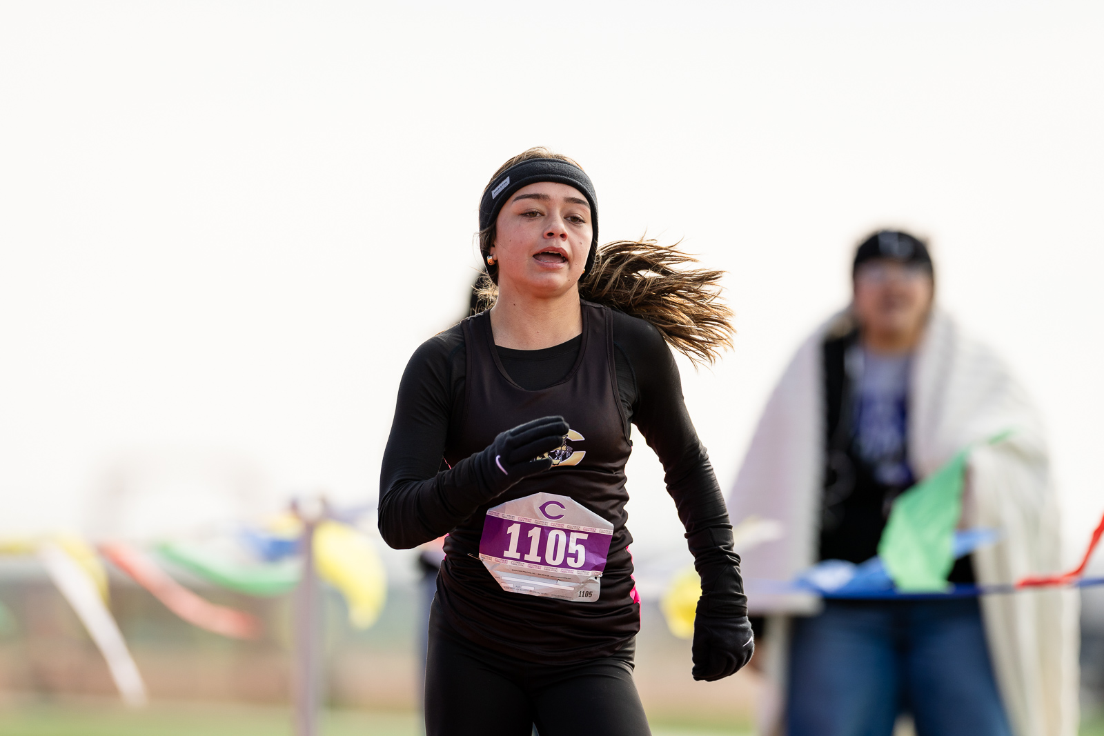3A-4A-district-xc-jpegJoe-pps-81 | Press Pass Sports Female runner wearing a black outfit and headband, mid-race with bib 1105, outdoors on a track or course.