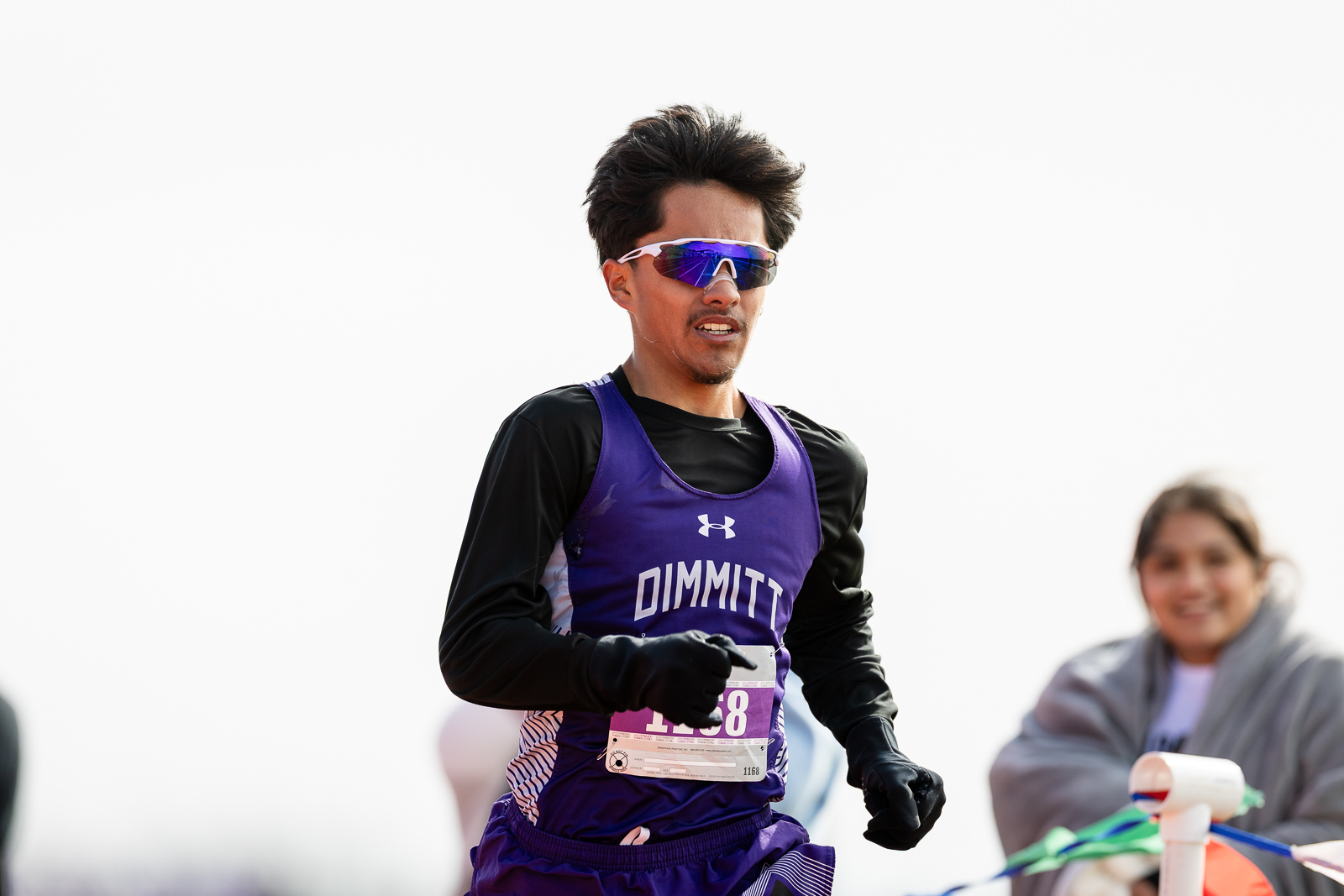 3A-4A-district-xc-jpegJoe-pps-98 | Press Pass Sports Male runner in a purple racing singlet and black sleeves, wearing reflective sunglasses, mid-race