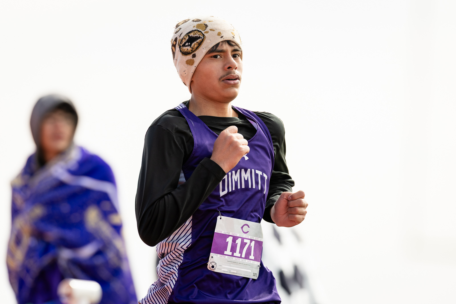 3A-4A-district-xc-jpegJoe-pps-103 | Press Pass Sports Young runner in a purple race singlet with bib 1171, fist raised, wearing a beige patterned headscarf, competing in a race.