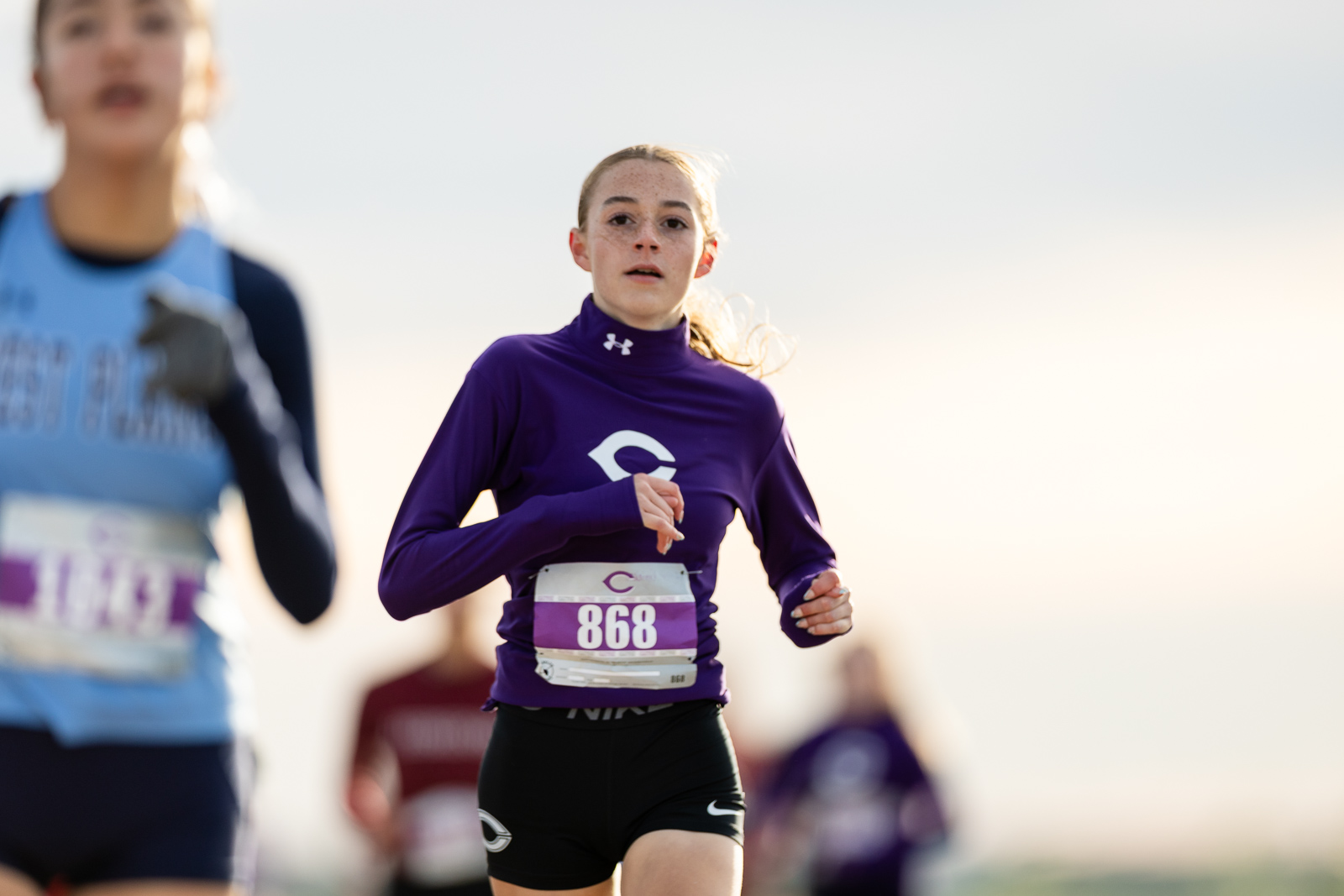 canyon-eagles-district-xc-jpegJoe-pps-5 | Press Pass Sports Young female runner in a purple long-sleeve top with bib 868, running toward the camera in a race.
