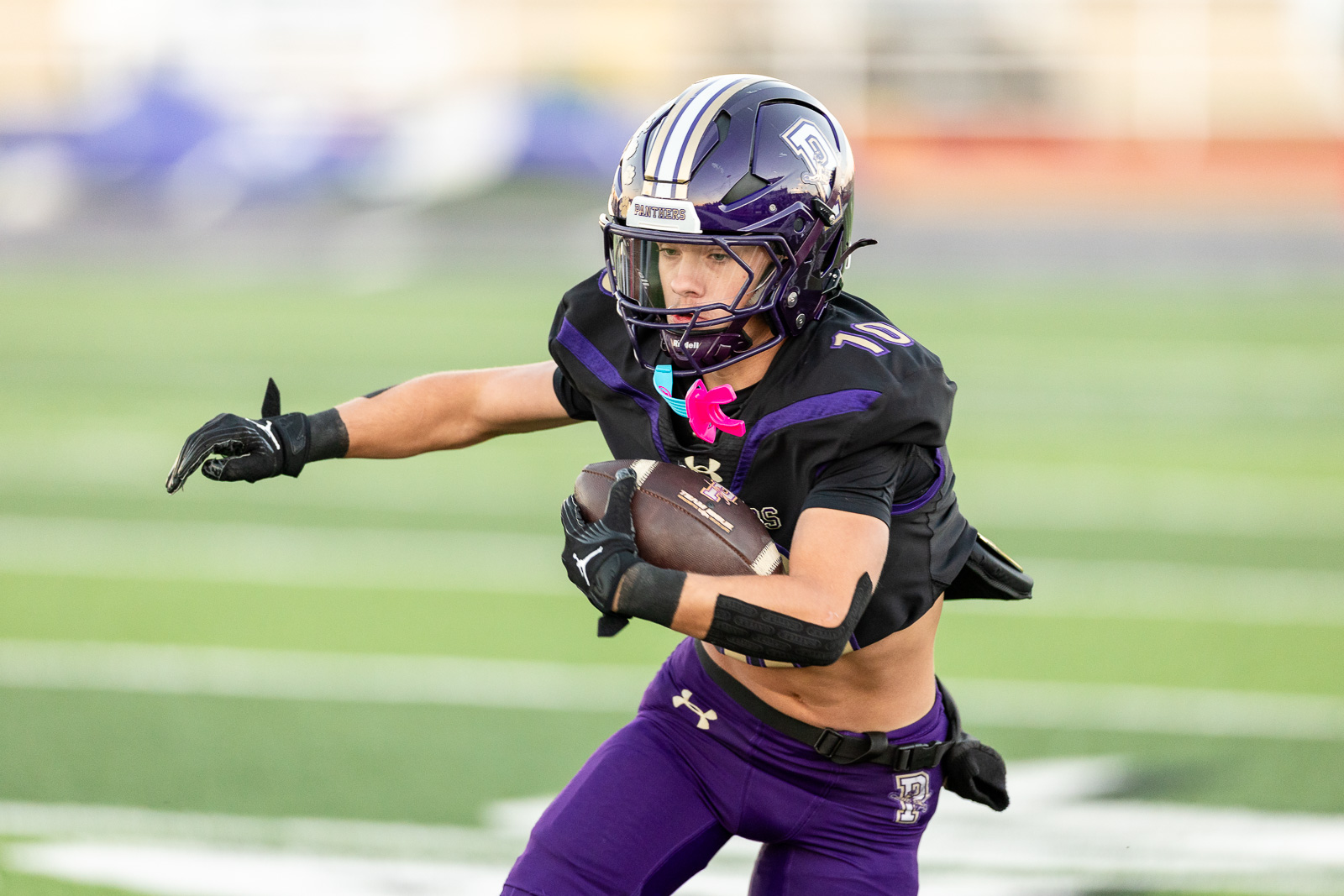 spearman-vs-panhandle-football-jpegJoe-pps-2 | Press Pass Sports Football player in a purple and black uniform runs with the ball on a green field during a game.
