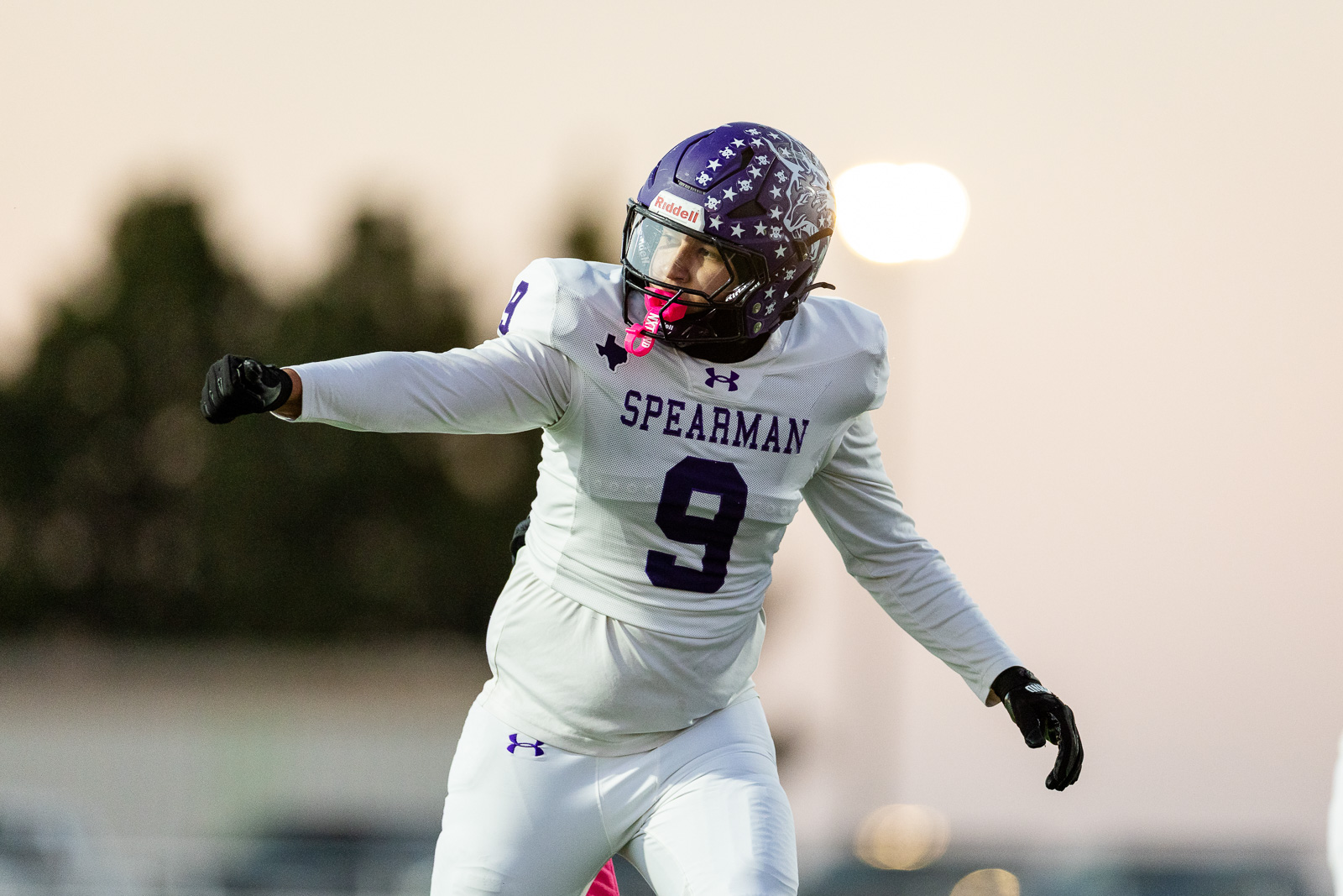 spearman-vs-panhandle-football-jpegJoe-pps-11 | Press Pass Sports American football player in a white Spearman uniform (number 9) extending his arm during a game, wearing a star-pattern helmet.