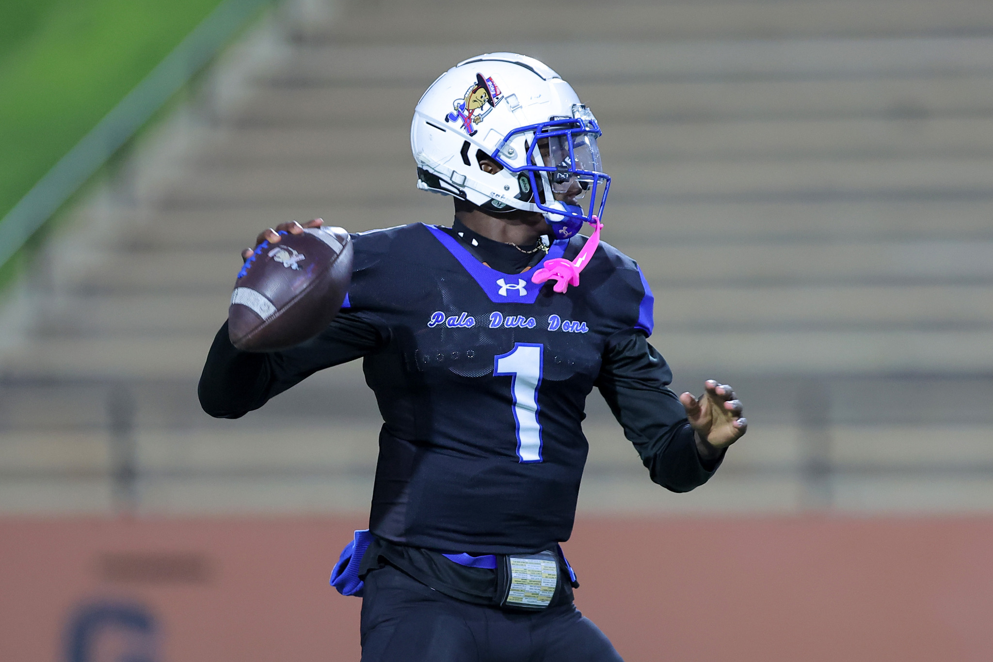 Football player in a dark Palo Duro jersey, number 1, sprinting on the field with a white helmet and blue facemask