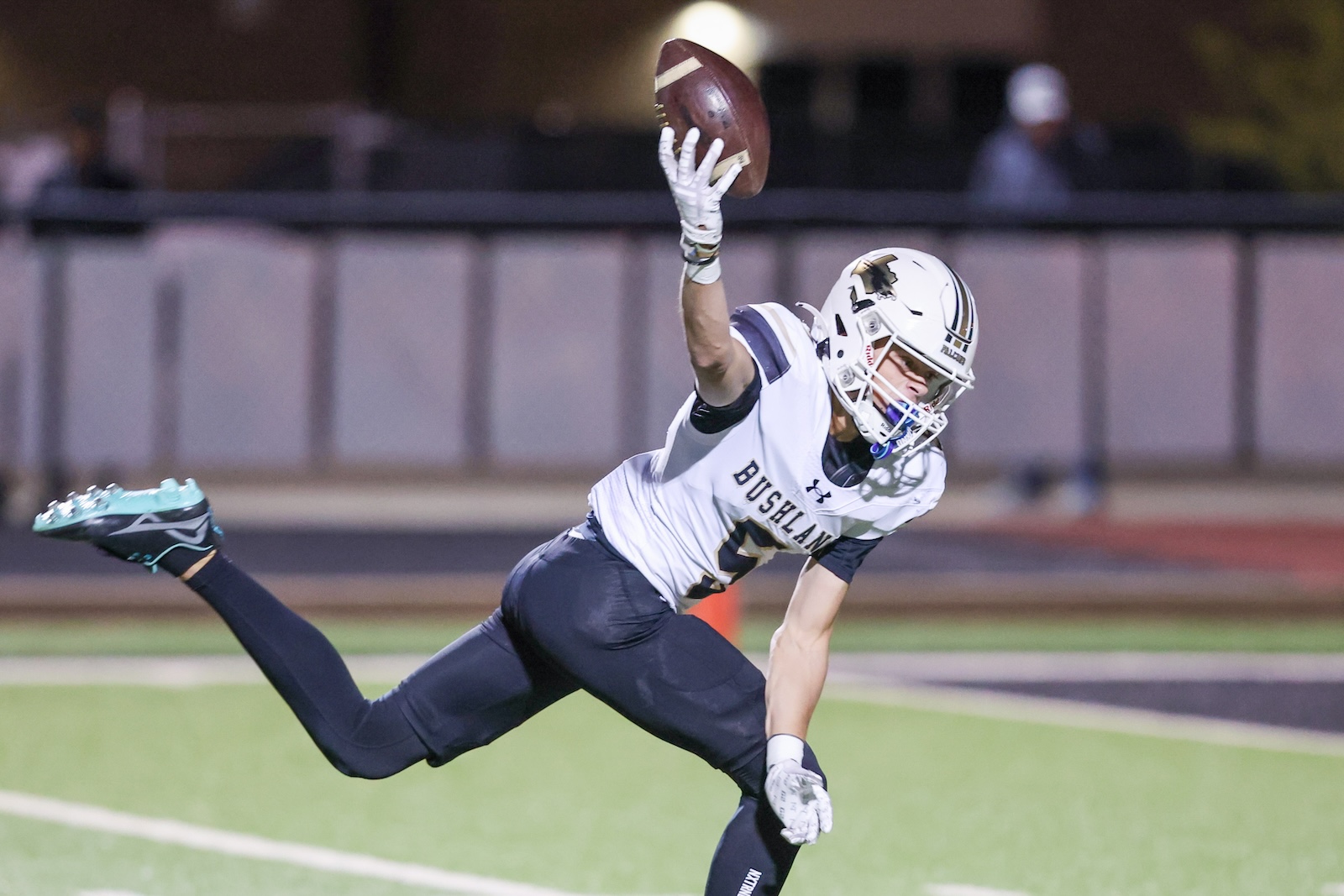 Seabolt Chase-17598 | Press Pass Sports Football player in white and navy reach lean to catch a pass at night on a turf field, uniform says Bushland.