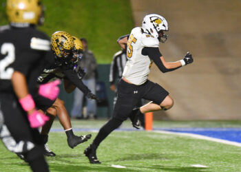 DSC_5375 | Press Pass Sports Football players sprinting on the field during a game, white jersey with number 25 leading the run behind a black-clad opponent in gold helmet