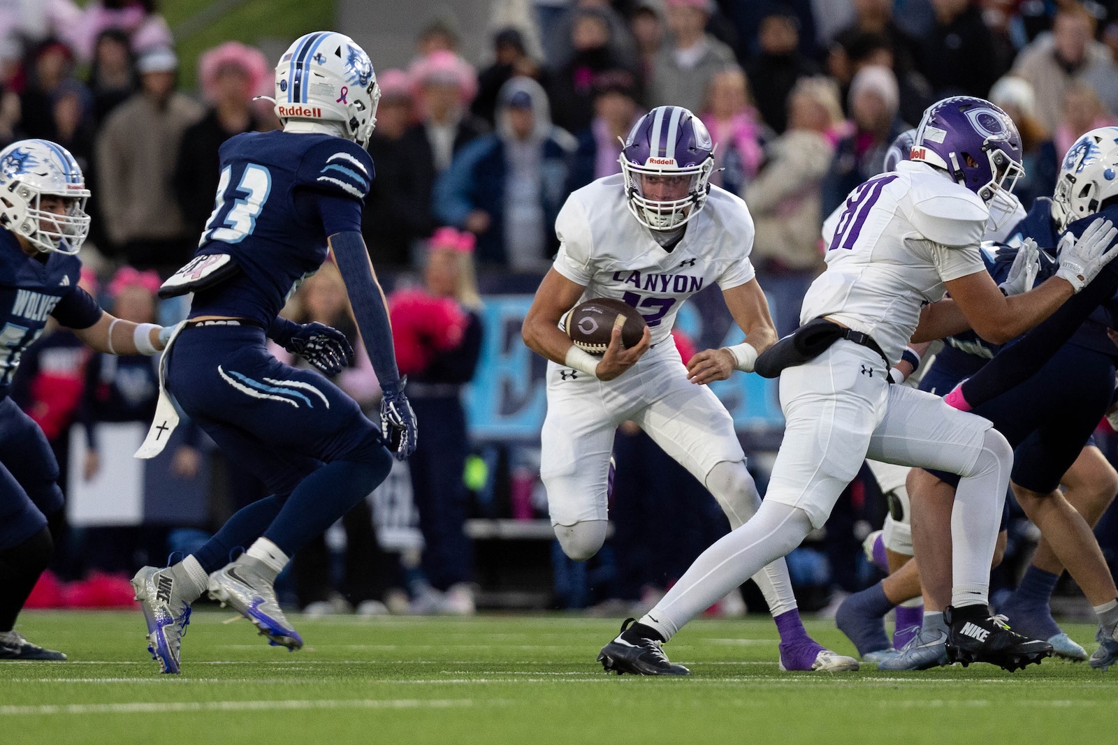 CHS-WPHS-FB-14 | Press Pass Sports Canyon football player in white uniforms running with ball as defenders close in on a turf field.
