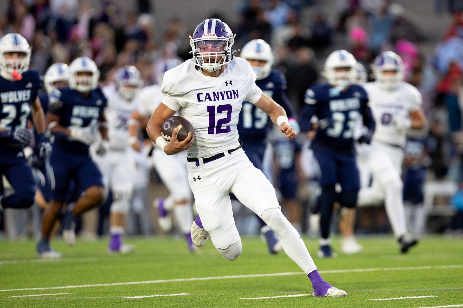 CHS-WPHS-FB-15 | Press Pass Sports Canyon quarterback wearing a white jersey with purple accents and number 12 runs with the football downfield.