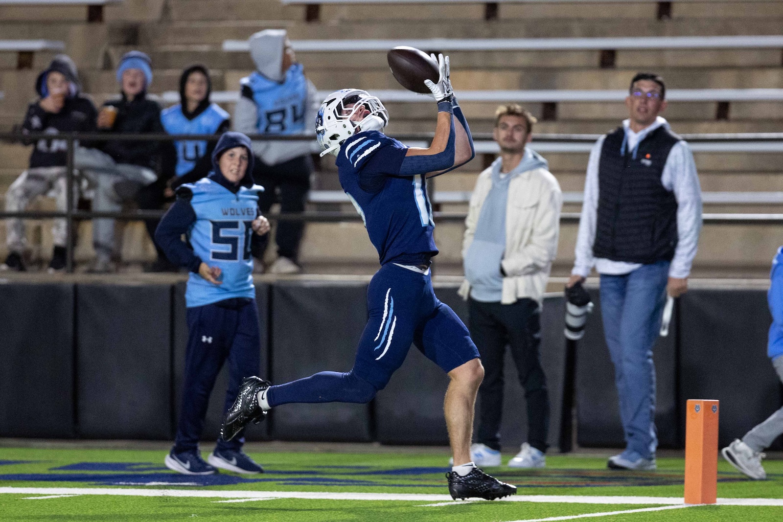 CHS-WPHS-FB-22 | Press Pass Sports Football player in blue catches a pass in the end zone with spectators watching from the stands in the background.