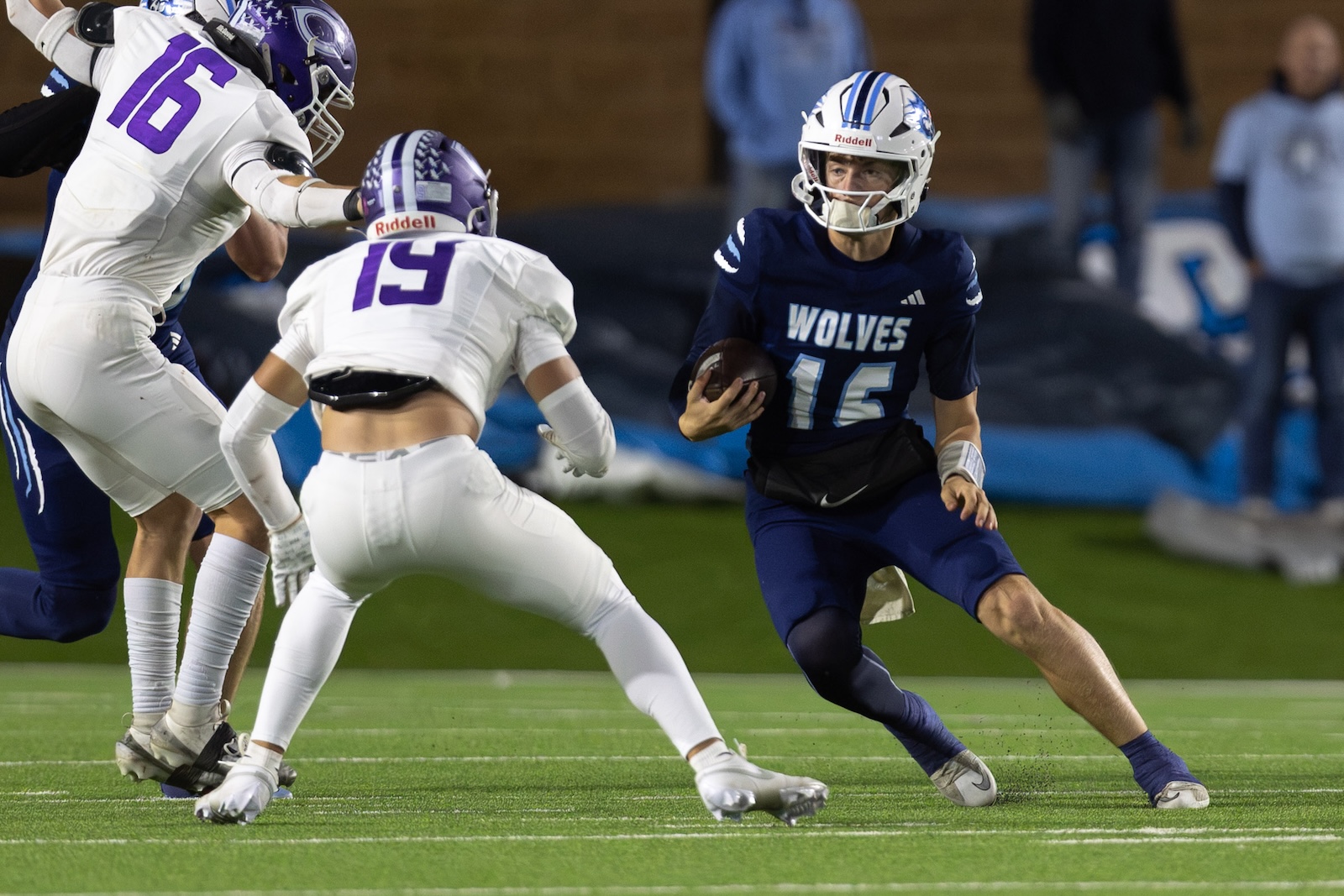 CHS-WPHS-FB-29 | Press Pass Sports Wolves player in blue #16 carrying the ball rushes forward as defenders close in.