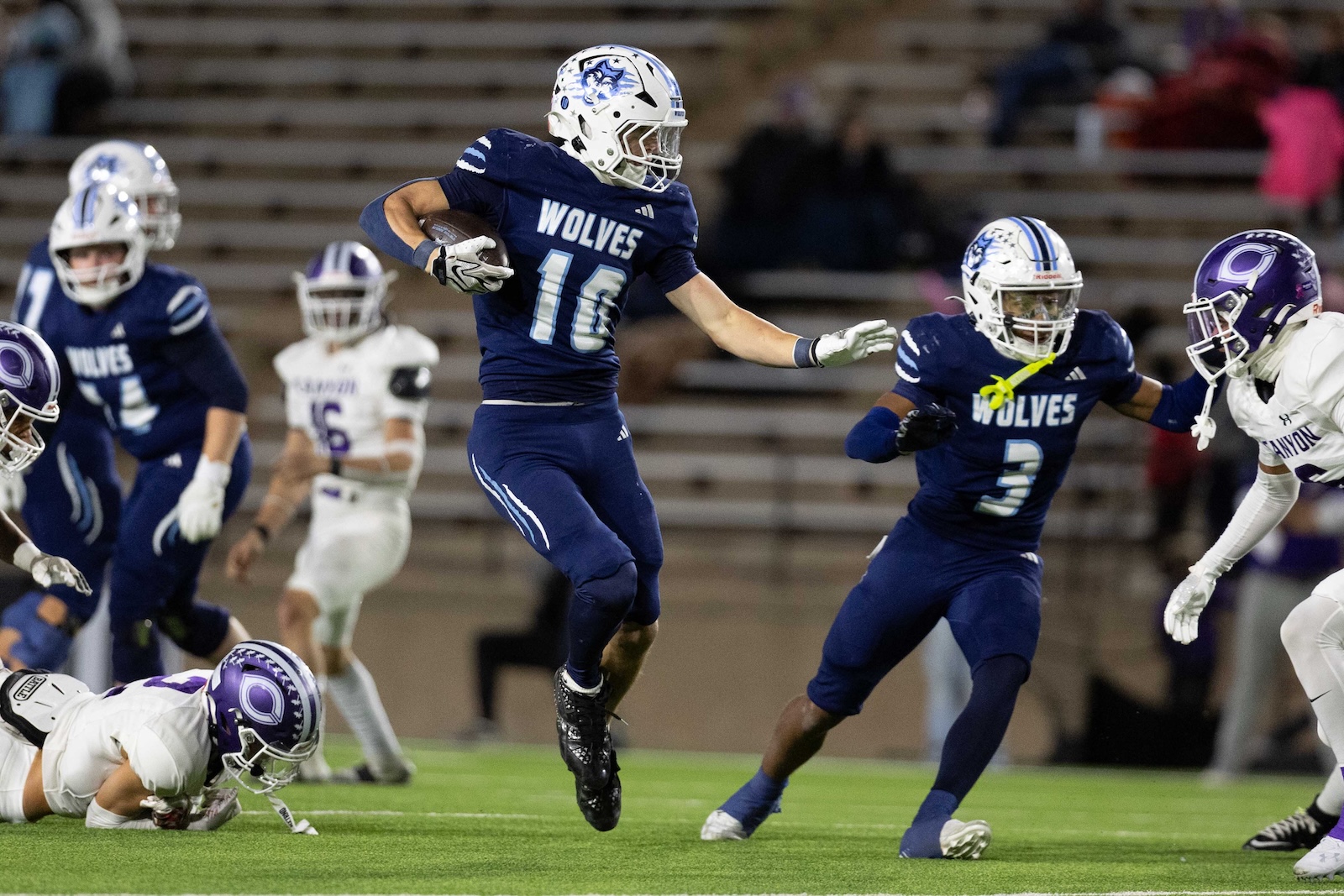 CHS-WPHS-FB-37 | Press Pass Sports A football player in a navy Wolves uniform #10 jumps midair clutching the ball while defenders close in.