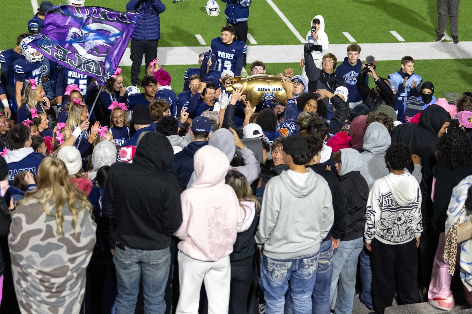 CHS-WPHS-FB-48 | Press Pass Sports Crowd of players and fans celebrate on a football field as a gold trophy is lifted aloft.