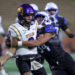 20261016-AWylie-PD-FB-035 | Press Pass Sports Two football players collide on the field during a tackle: a white-uniformed player with a purple 'WYLIE' helmet holds the ball as a dark-shirted defender grabs him.