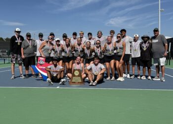 IMG_0978 | Press Pass Sports Group of young tennis players and coaches wearing medals, posing with a trophy on a sunny tennis court.
