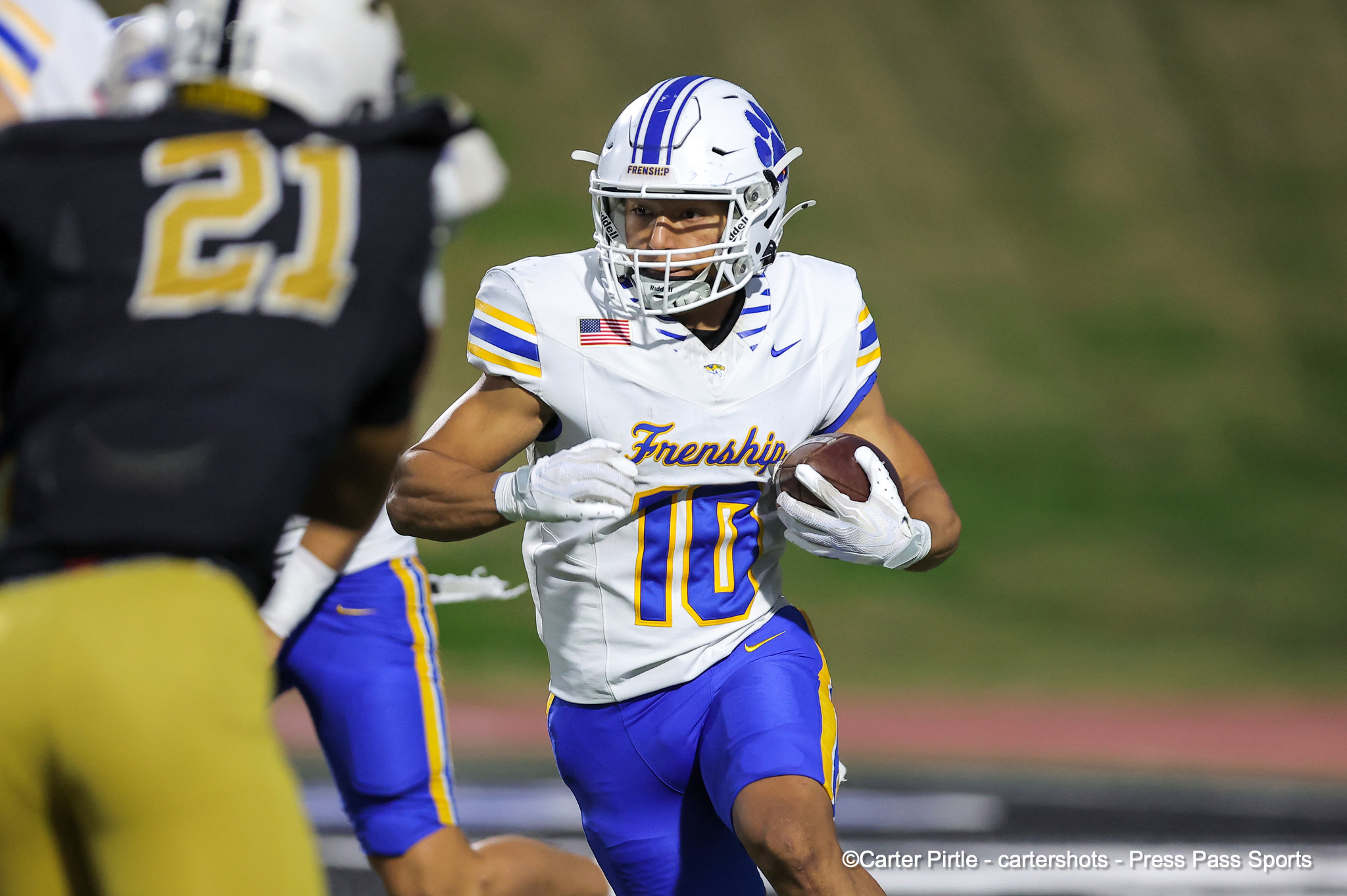 Football player wearing a white blue-yellow uniform runs with the ball during a game (number 10 visible).