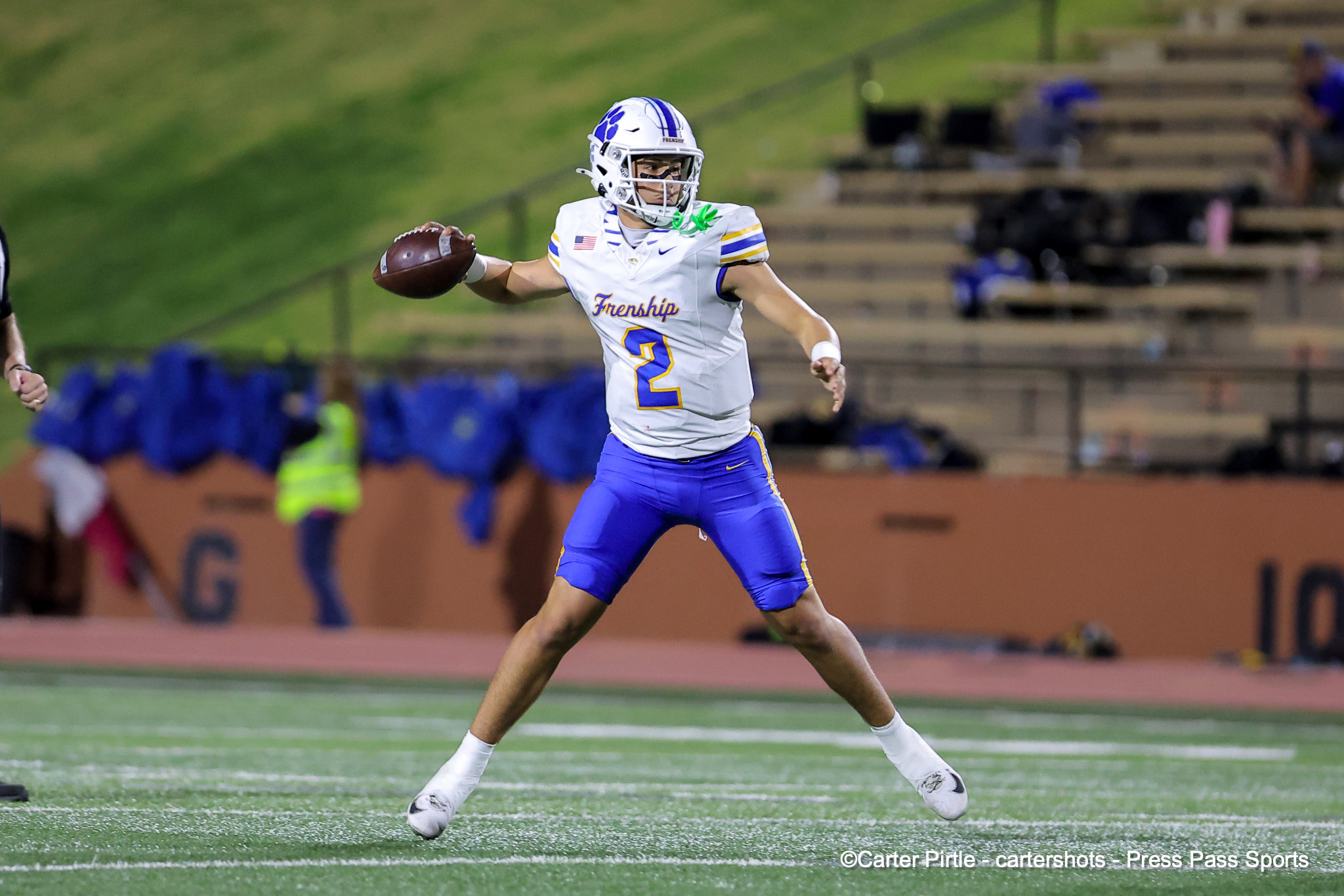 American football player in white and blue uniform (number 2) running with the ball on a green turf field during a game.