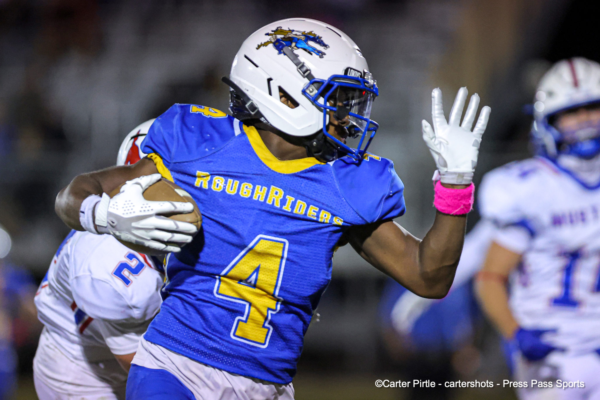 Roughriders football player in blue and yellow jersey runs with the ball during a game.