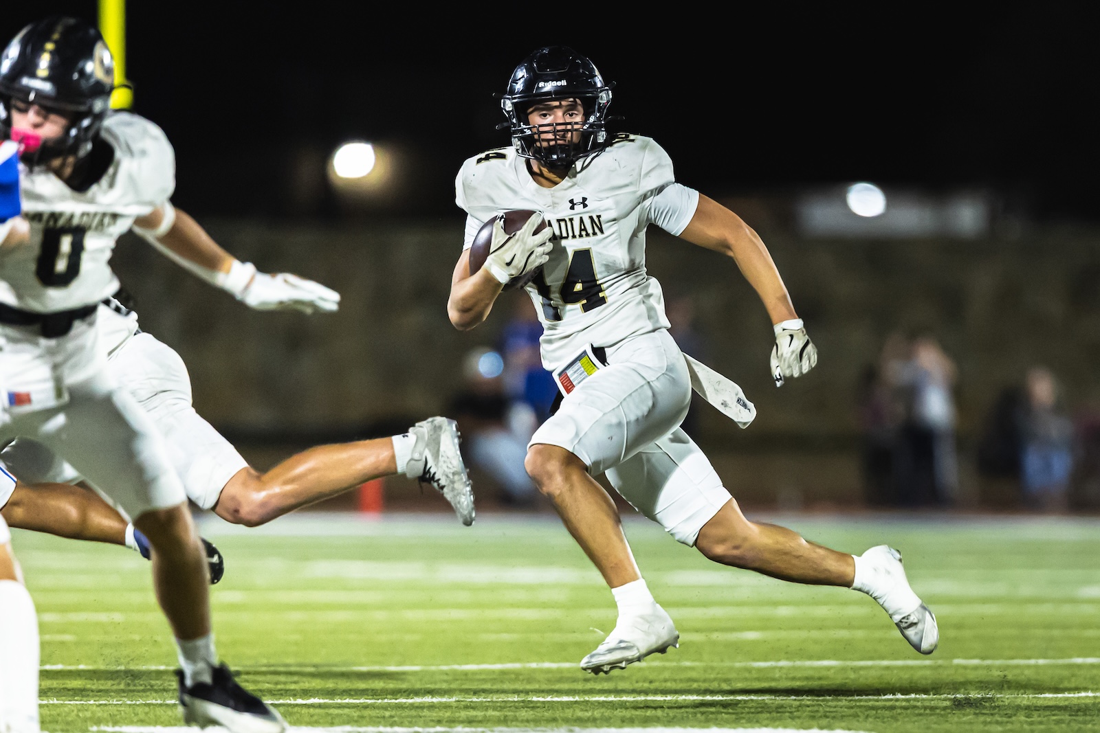 DE3_0035 | Press Pass Sports Football player in a white uniform runs with the ball during a night game on a lit field