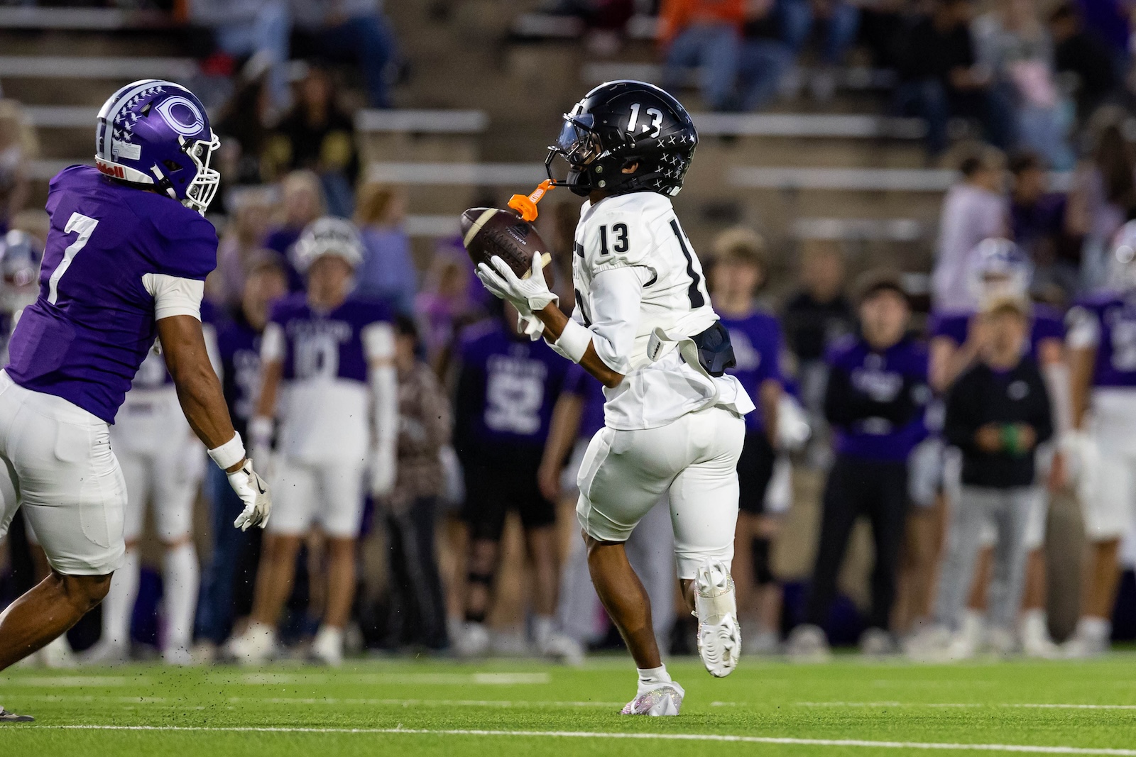 RHS-CHS-FB-8 | Press Pass Sports Football player in white jersey #13 carries the ball while a purple-clad defender rushes toward him.