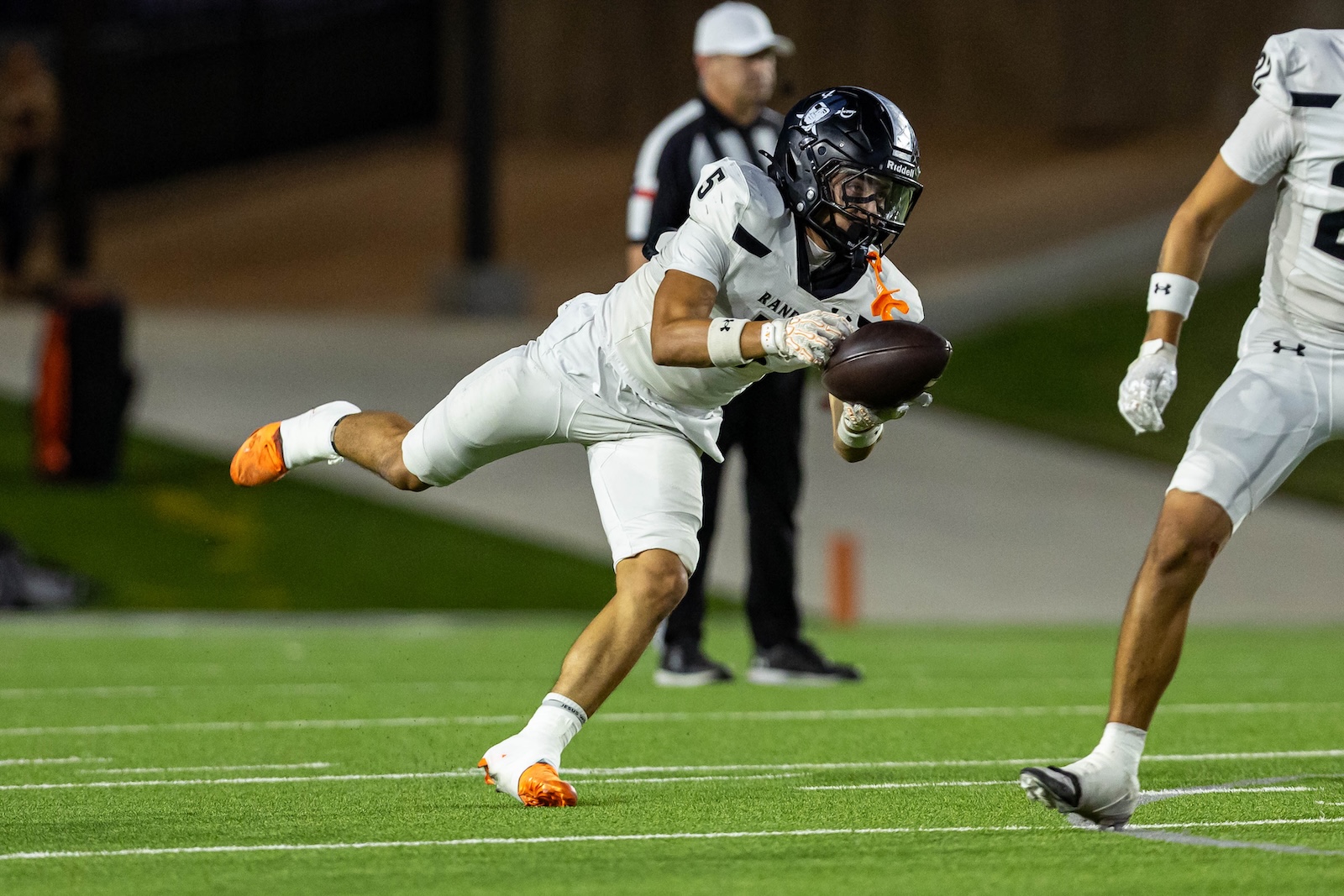 RHS-CHS-FB-10 | Press Pass Sports Football player in white uniform diving to catch a ball near the sideline, orange cleats visible, night game on artificial turf