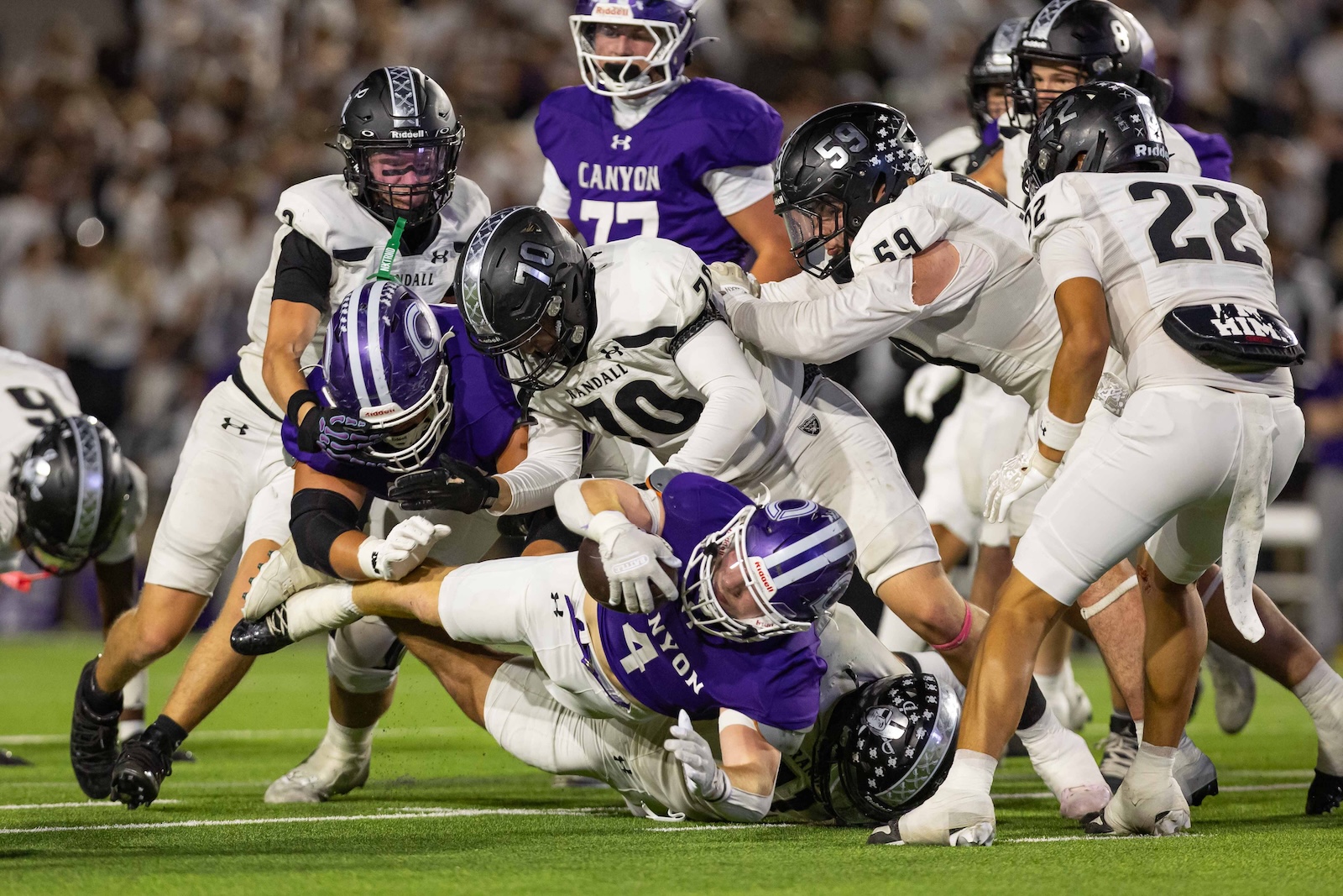 RHS-CHS-FB-15 | Press Pass Sports College football players in white uniforms tackle a purple-clad ball carrier during a crowded scramble on the field.