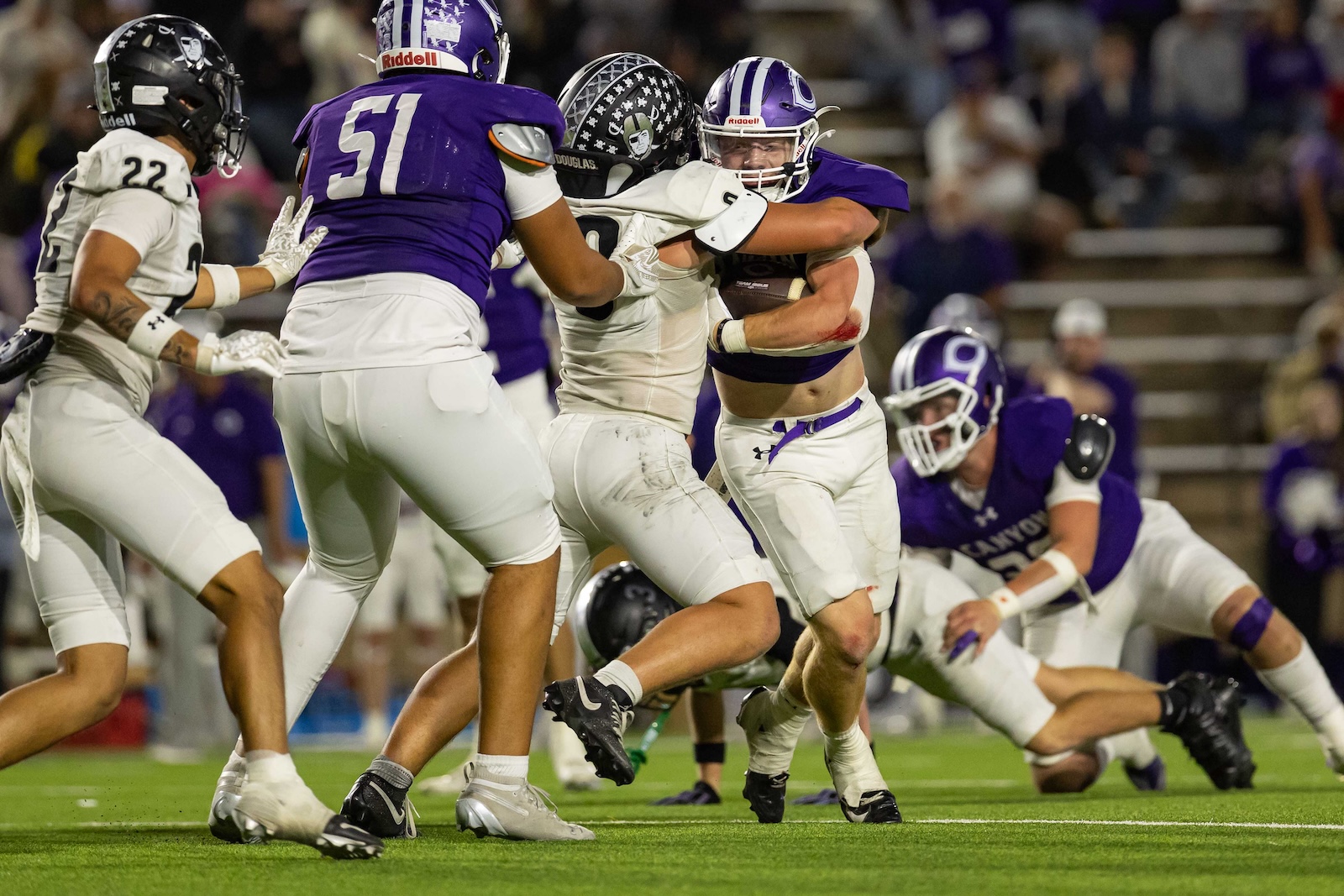 RHS-CHS-FB-25 | Press Pass Sports Players in purple and white uniforms collide for the football on a bright green field during a game.