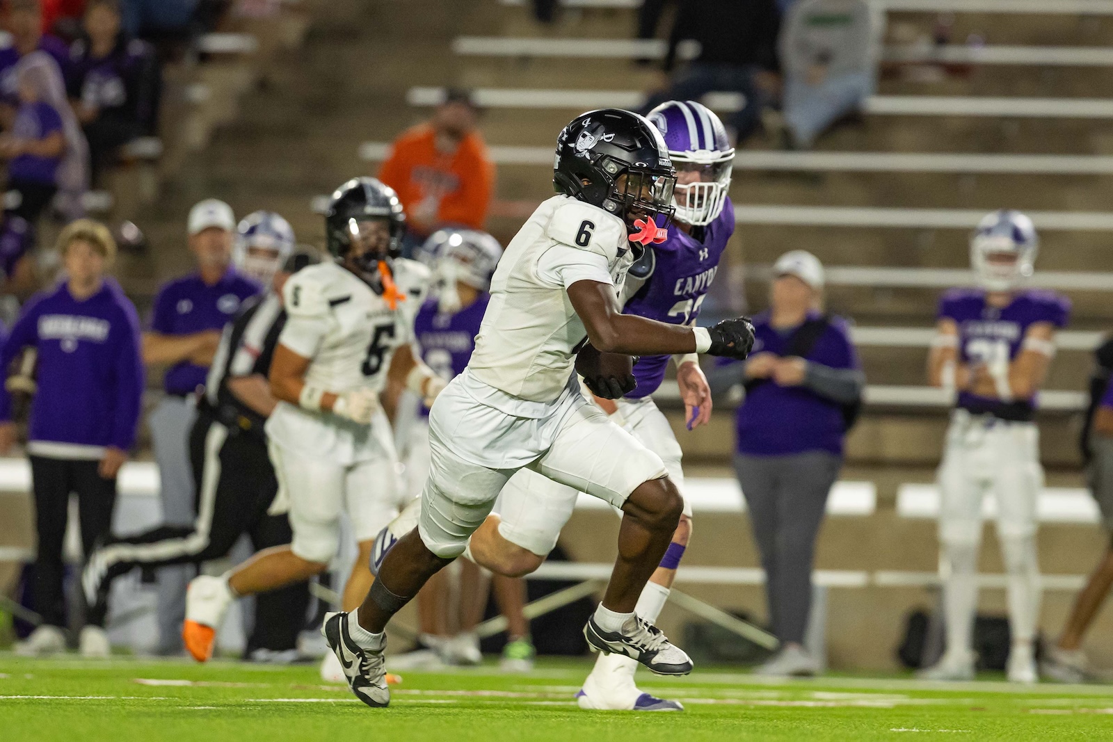 RHS-CHS-FB-28 | Press Pass Sports Wide receiver in white with number 6 running the ball down the field, pursued by a purple.team defender.