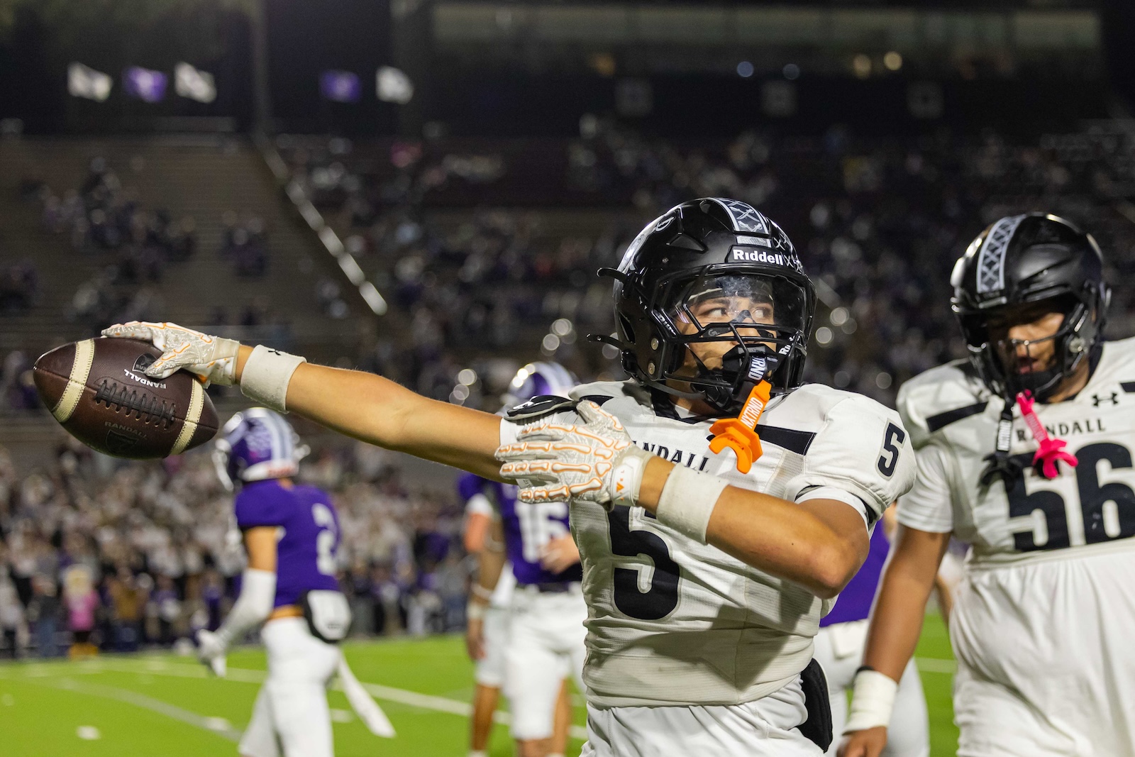 RHS-CHS-FB-31 | Press Pass Sports Football player in a white uniform #5 extends his left arm and catches a ball during a night game, stadium crowd in the background.