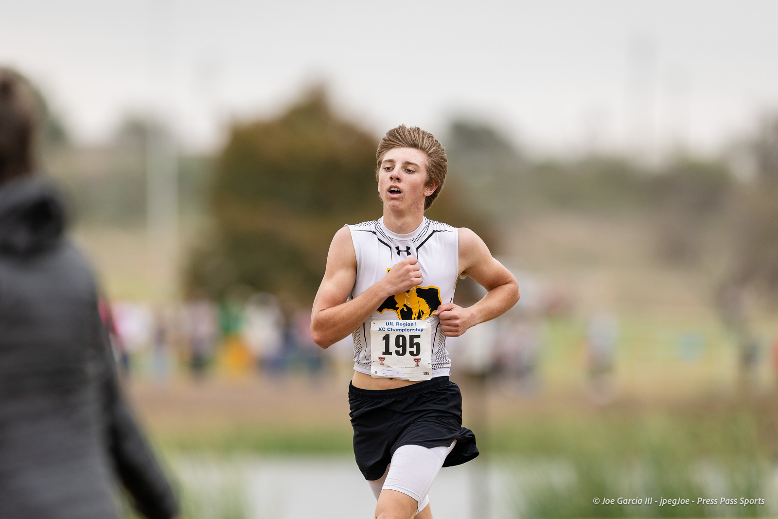 regional-xc-lubbock-2026-jpegJoe-pps-16 | Press Pass Sports Male cross-country runner wearing bib 195 sprinting on course with blurred spectators in background at a UIL Region 1 XC Championship event