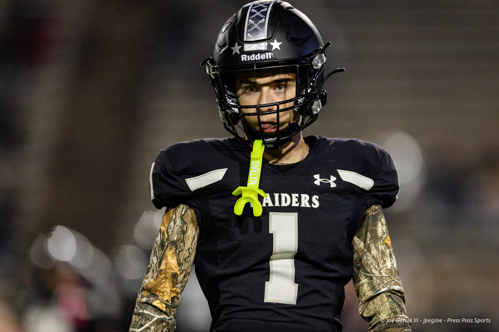 west-plains-vs-randall-2026-jpegJoe-pps-21 | Press Pass Sports Football player in black Raiders jersey #1 with a neon mouthguard hanging from his mouth on the field.