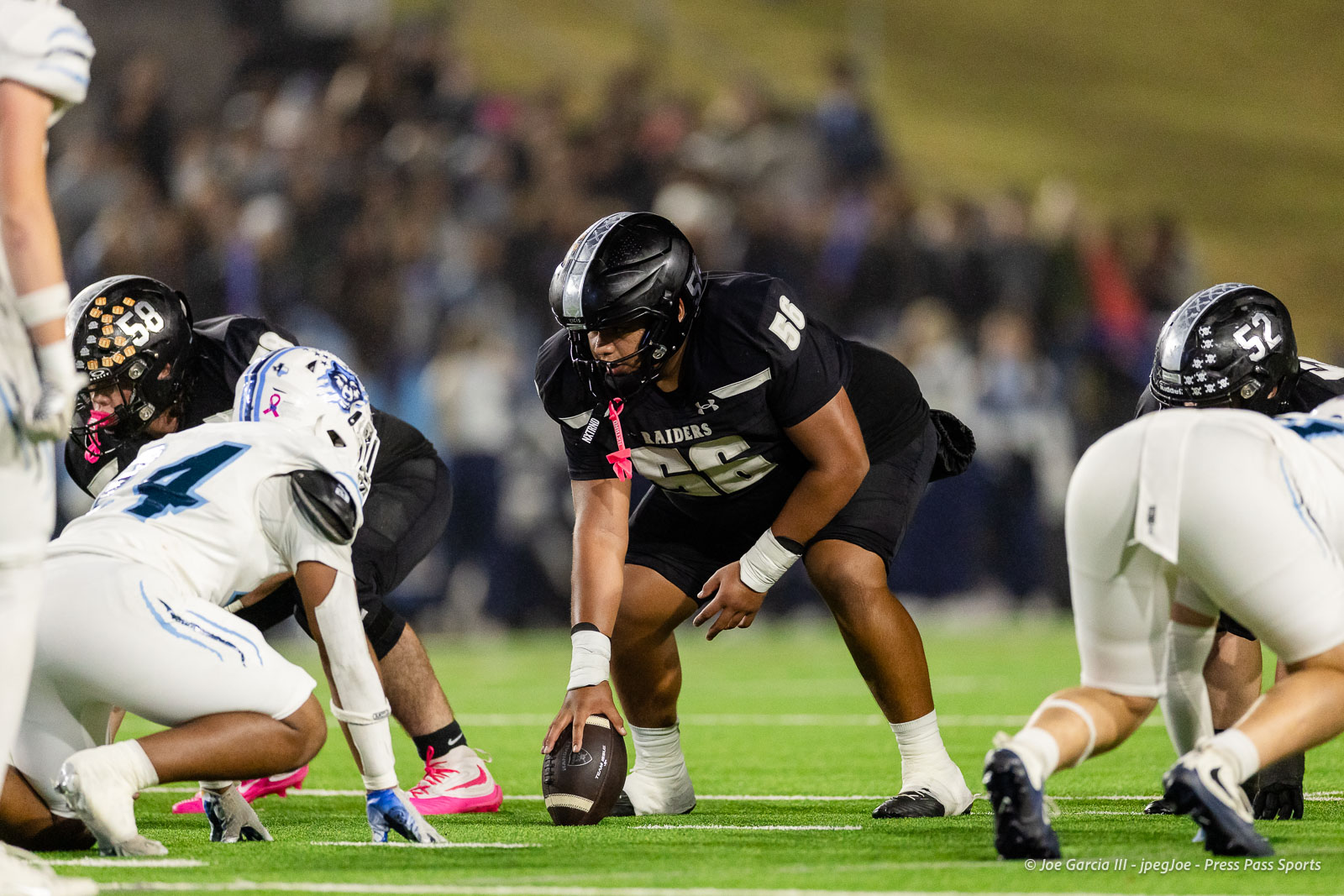 west-plains-vs-randall-2026-jpegJoe-pps-27 | Press Pass Sports Raiders player in black jersey (#46) crouches over the ball at the line of scrimmage, surrounded by opposing white-uniform defenders and teammates.