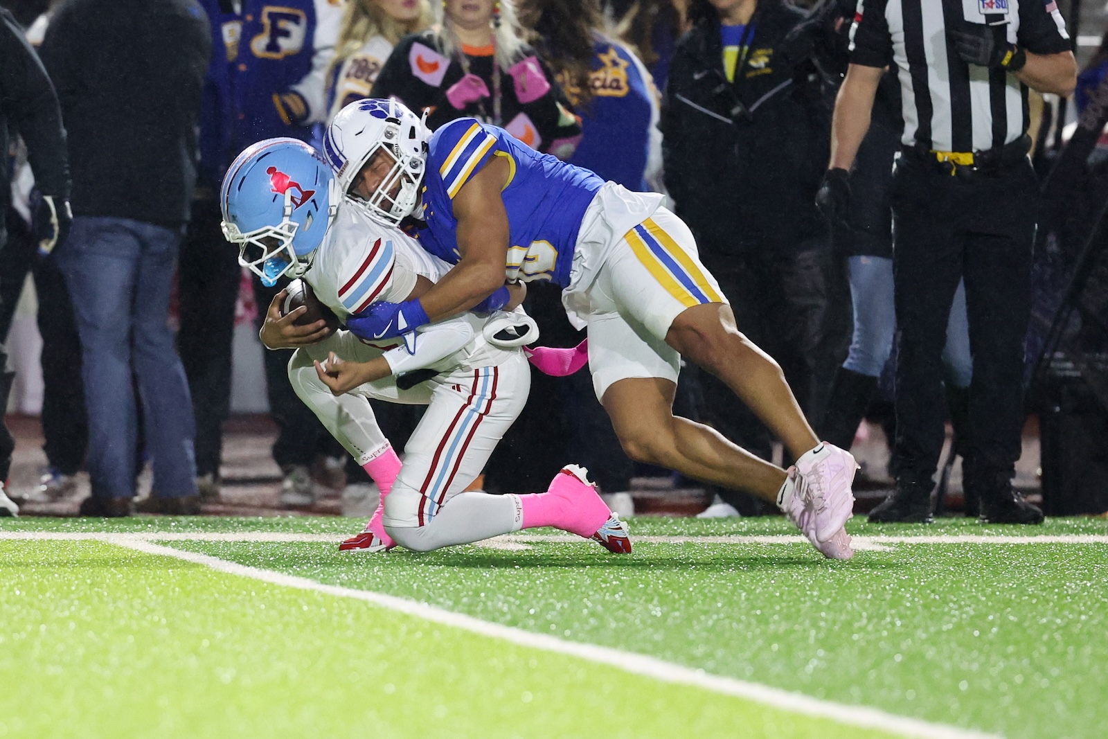 Seabolt Chase-18915 | Press Pass Sports Football player in blue and gold tackles a runner in white with the ball, near the sideline on a bright green field